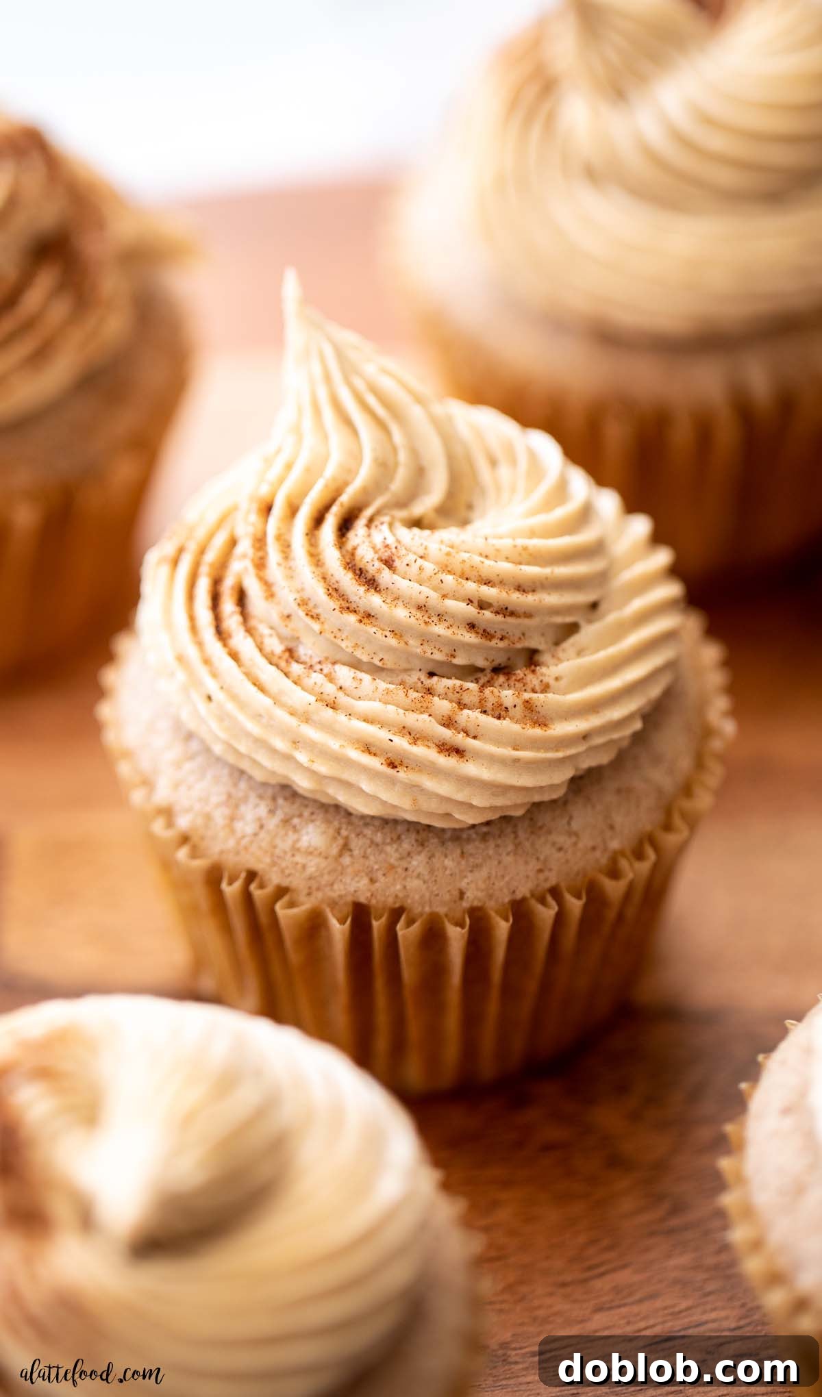 homemade snickerdoodle cupcake with brown sugar frosting on wood cake stand