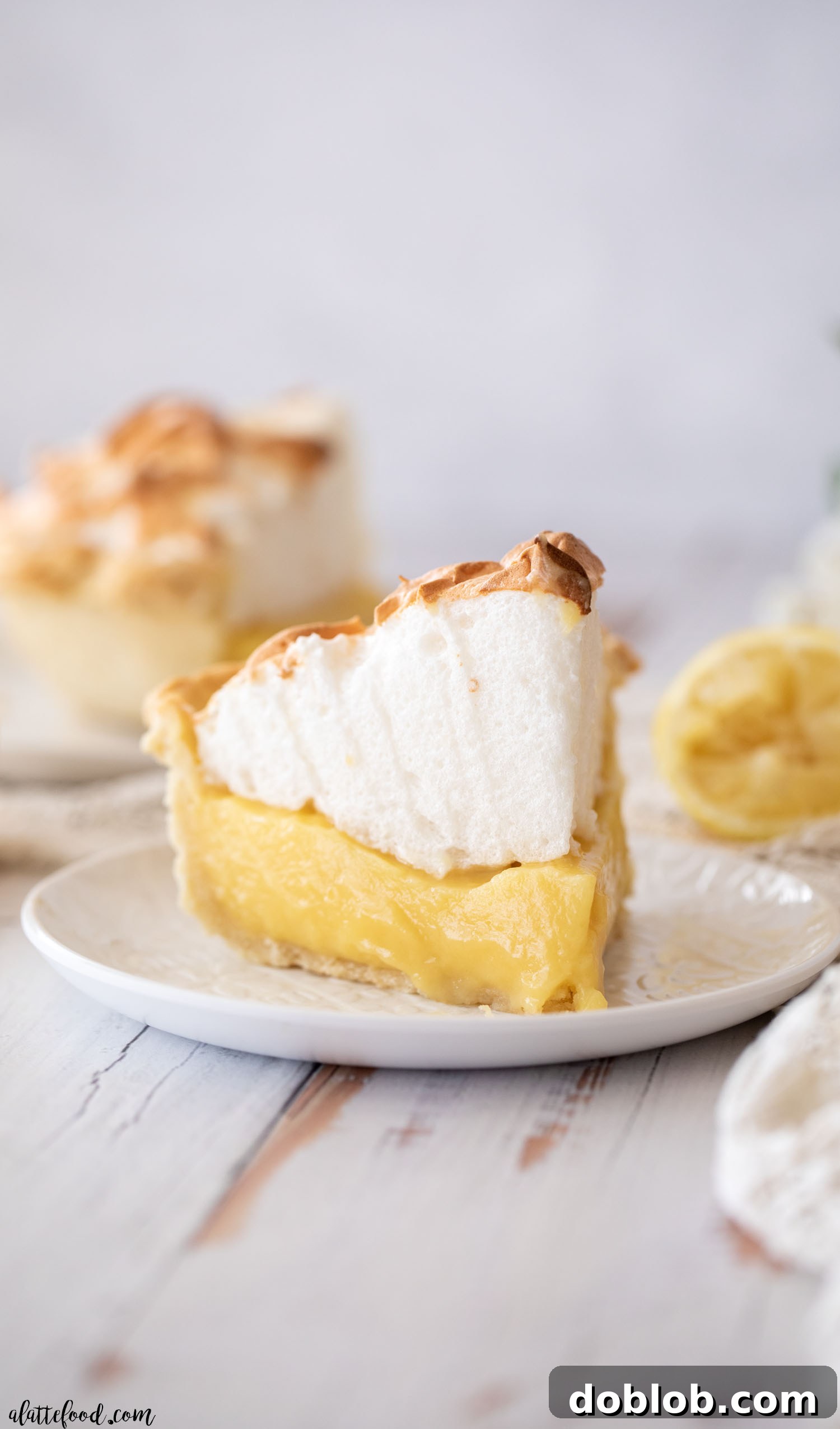 lemon pie with meringue sliced and sitting on white plate