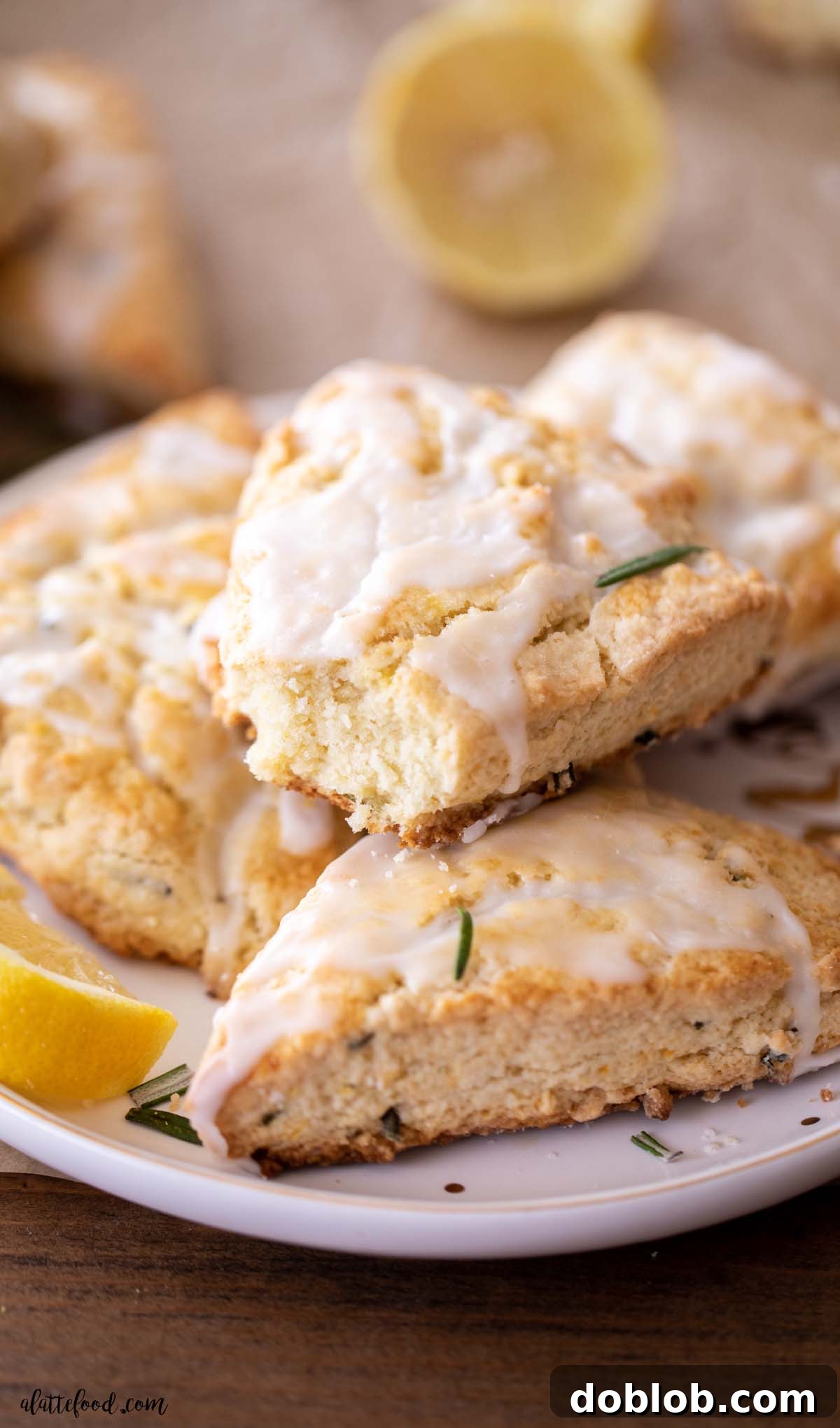 homemade lemon rosemary scones with lemon glaze stacked on white plate
