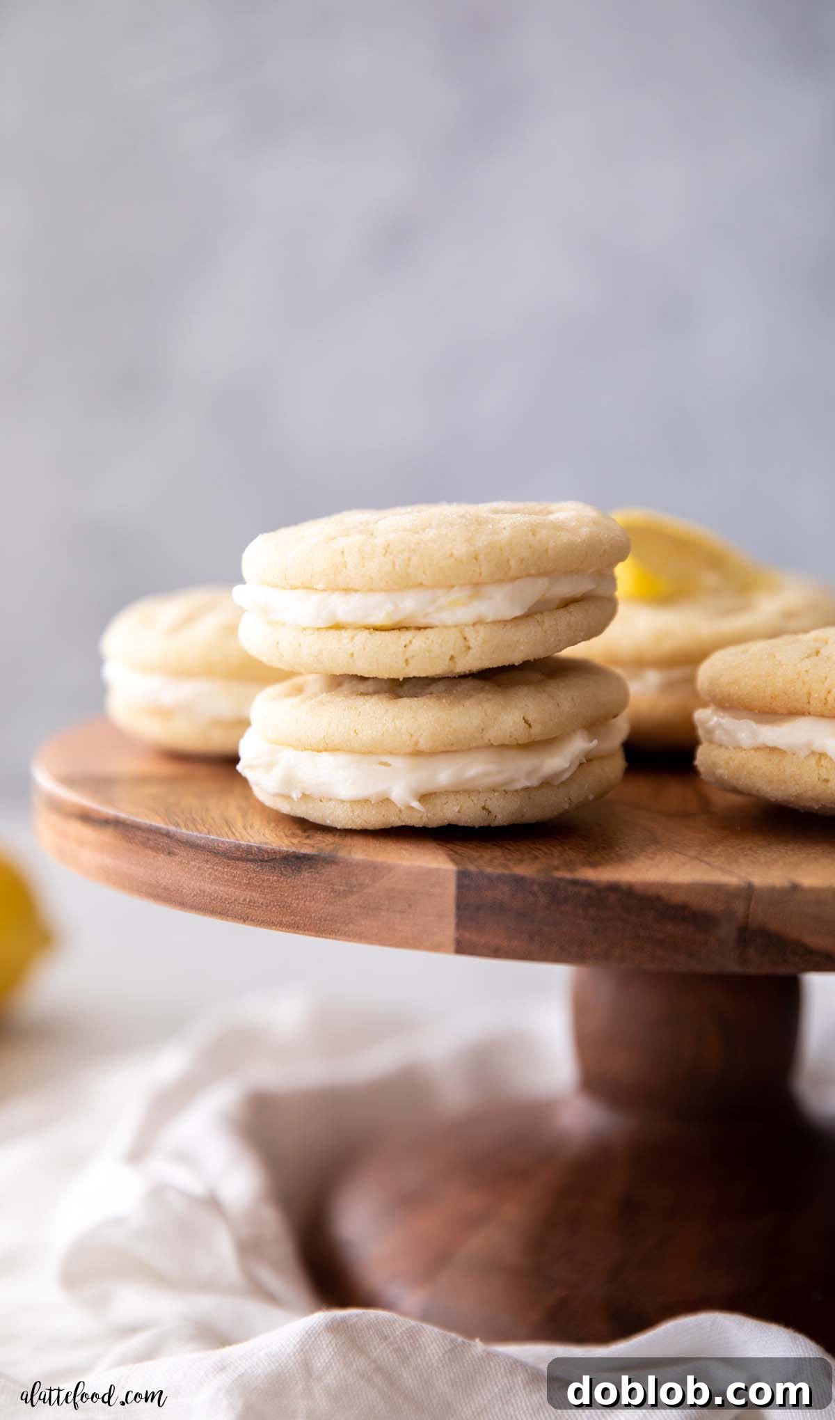 Lemon Sugar Cookie Sandwiches stacked on a wooden cake stand.