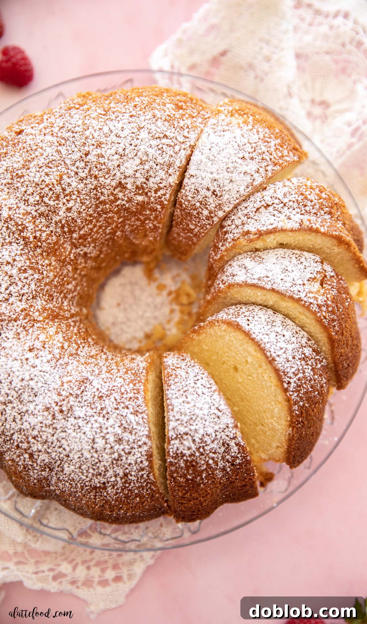 Multiple slices of creamy, moist cream cheese pound cake arranged elegantly on a glass plate, generously dusted with powdered sugar.