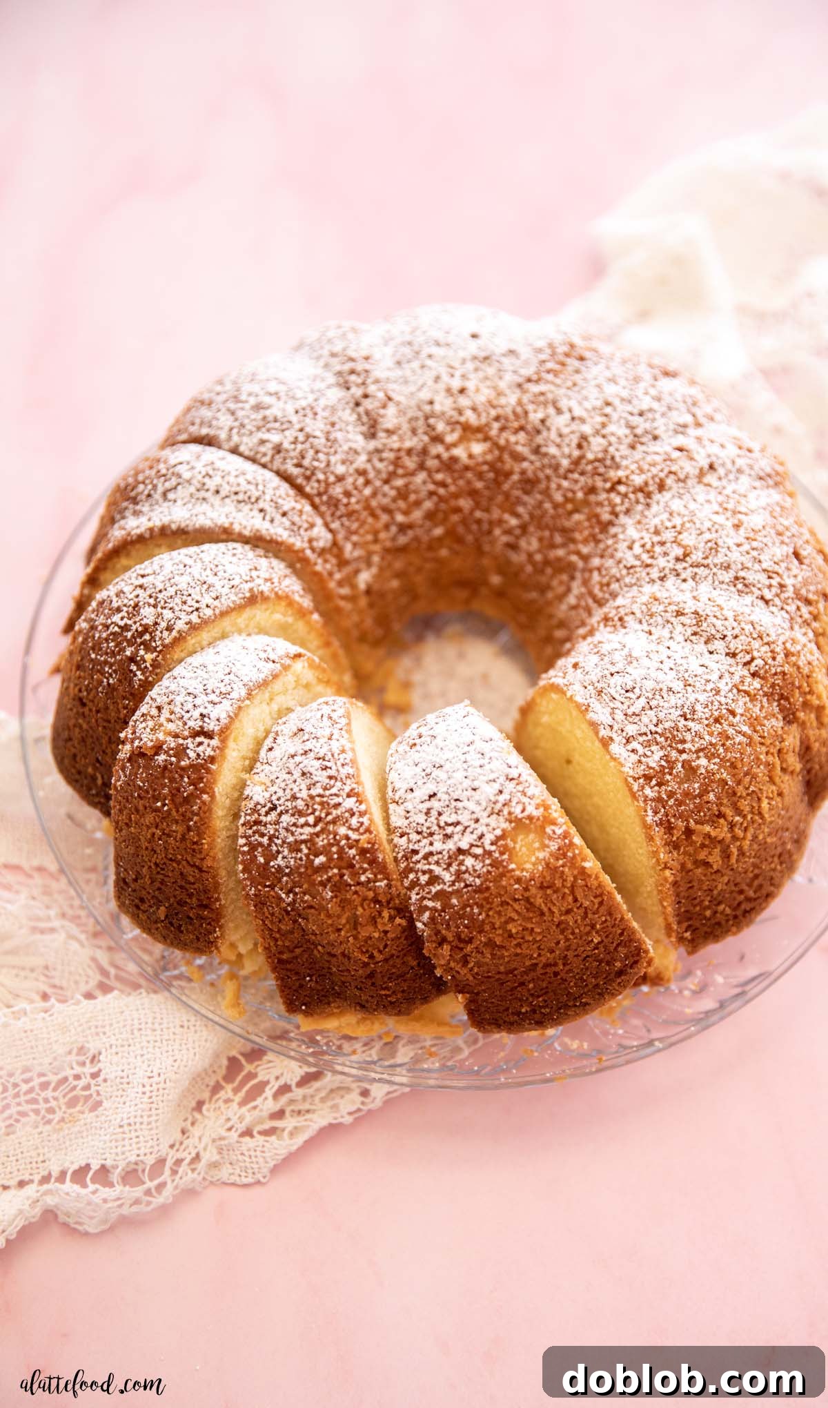 A sliced homemade pound cake with cream cheese, presented beautifully on a glass plate, showing its dense and moist texture.