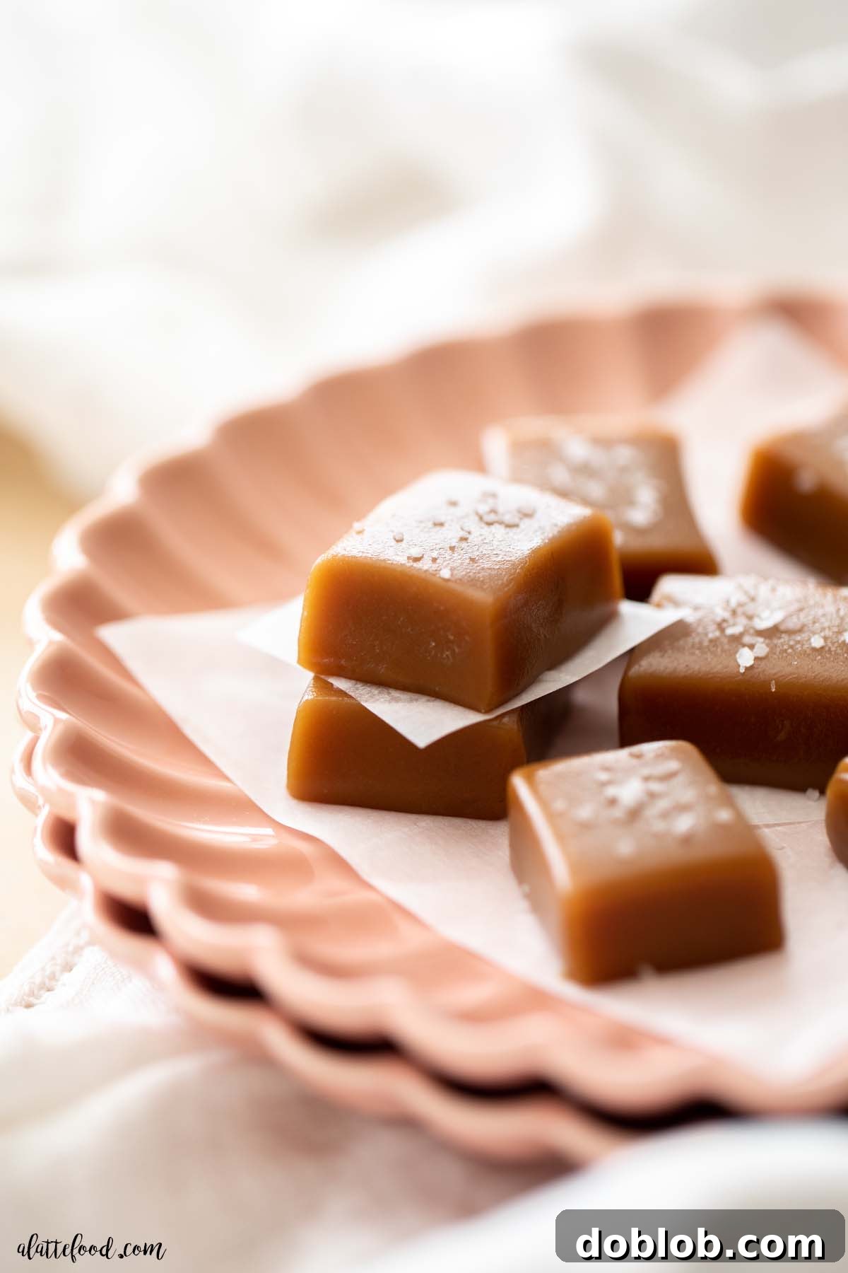 Caramel candies with sea salt stacked on a pink plate.