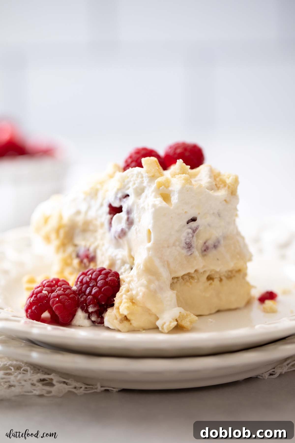 Slice of White Chocolate Raspberry Pudding with fresh raspberries on white plates, showing intricate layers.