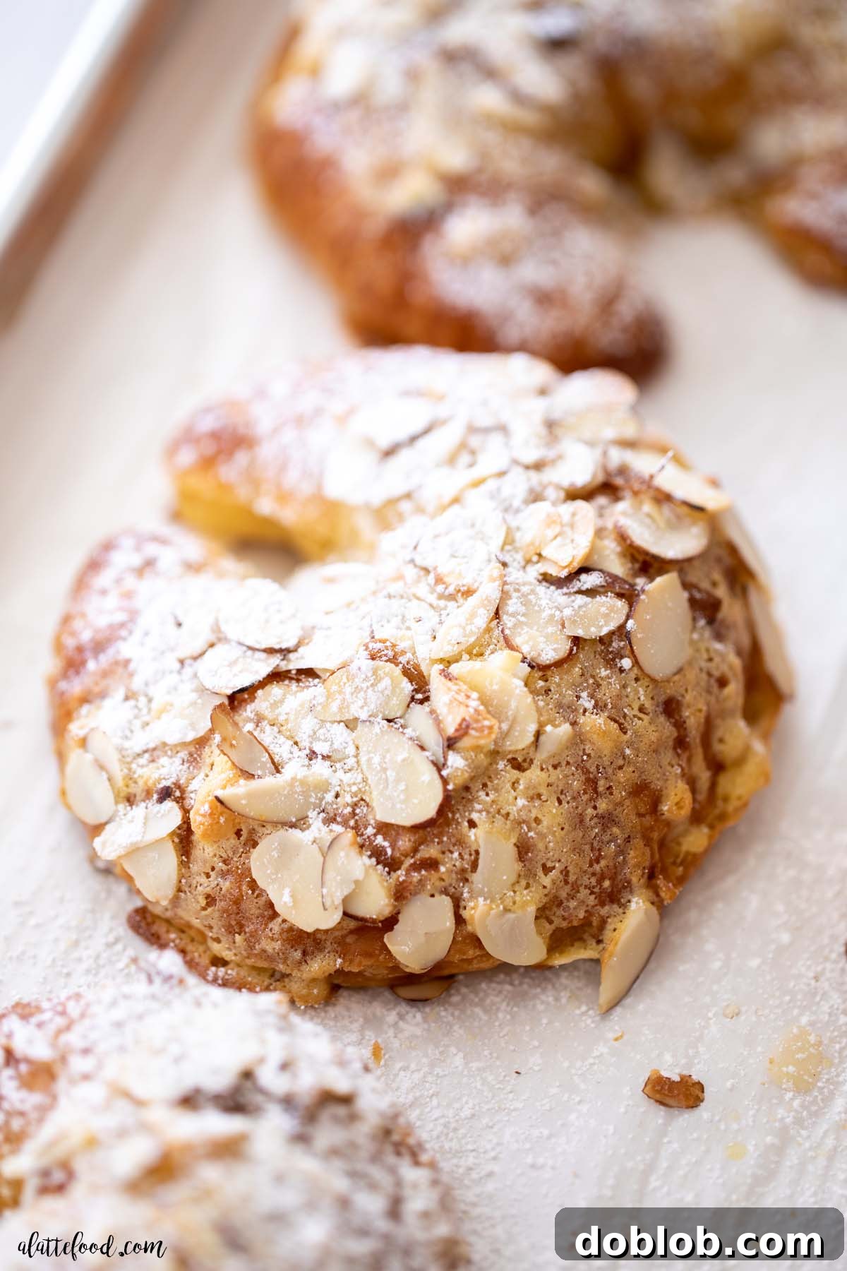 These almond croissants are made with an almond paste (aka almond frangipane) and they are flaky and buttery and such a simple French pastry! baked almond croissants with toasted almonds and frangipane on parchment paper. A classic French pastry.