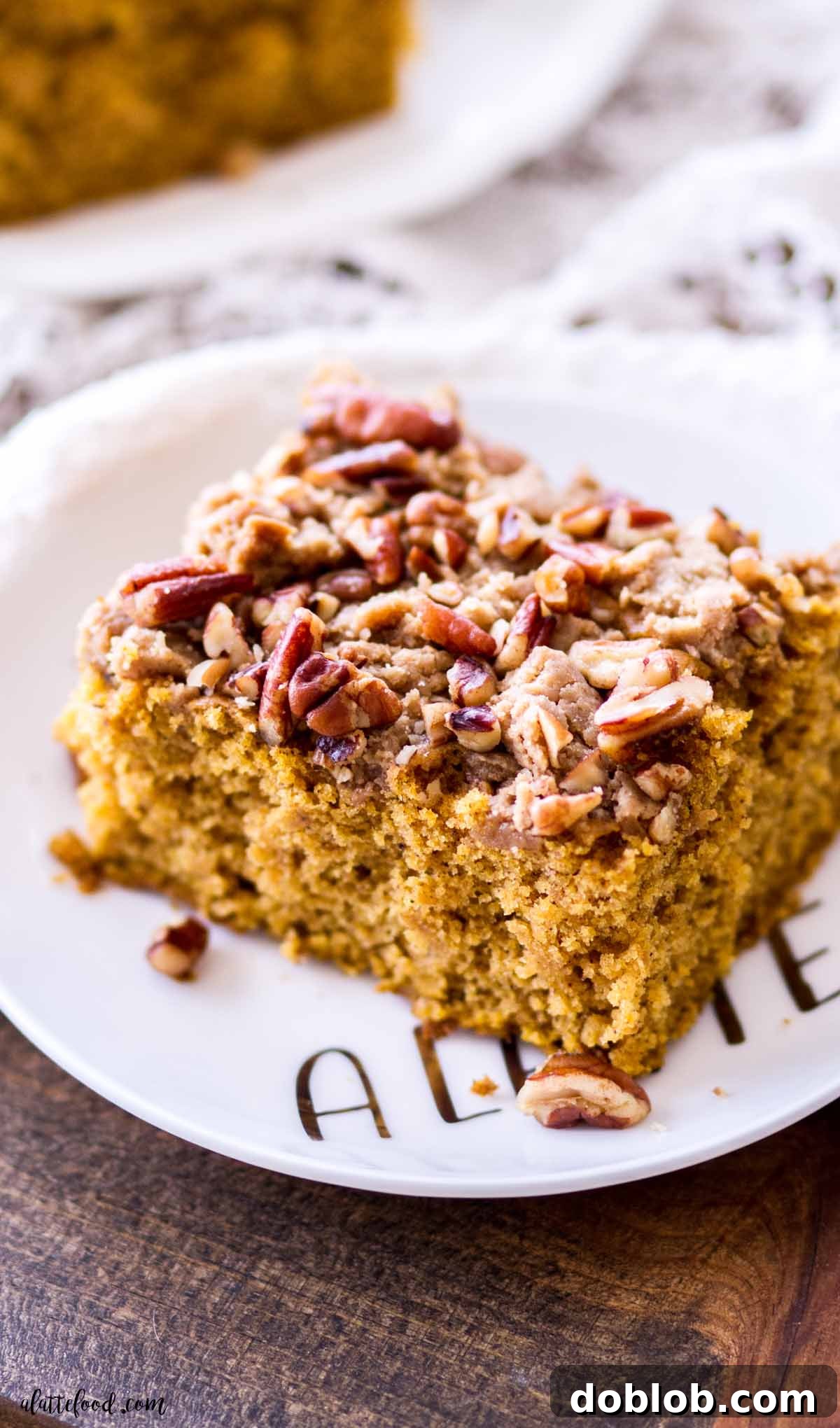 This moist Pumpkin Coffee Cake with brown sugar streusel is an easy and delicious fall breakfast. Pumpkin coffee cake with toasted pecans on a white dessert plate, perfect for fall breakfast.