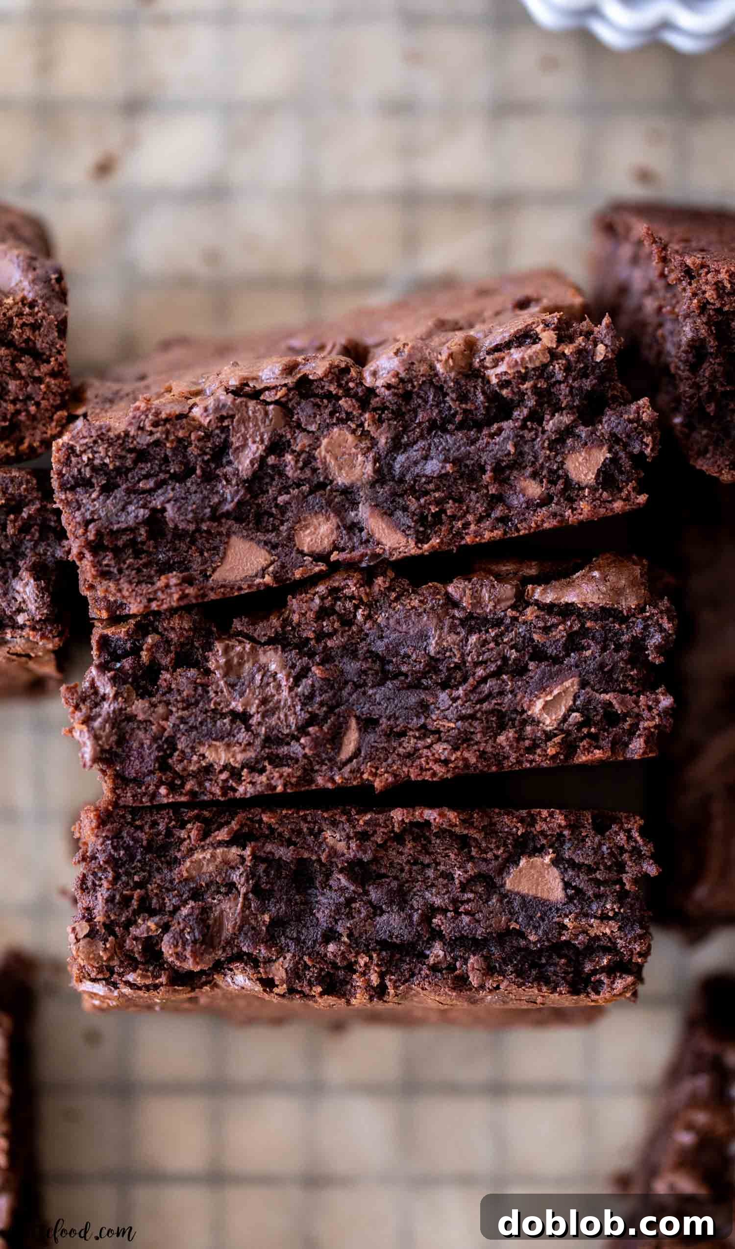 three chocolate fudge brownies standing up on a black wire cooling rack