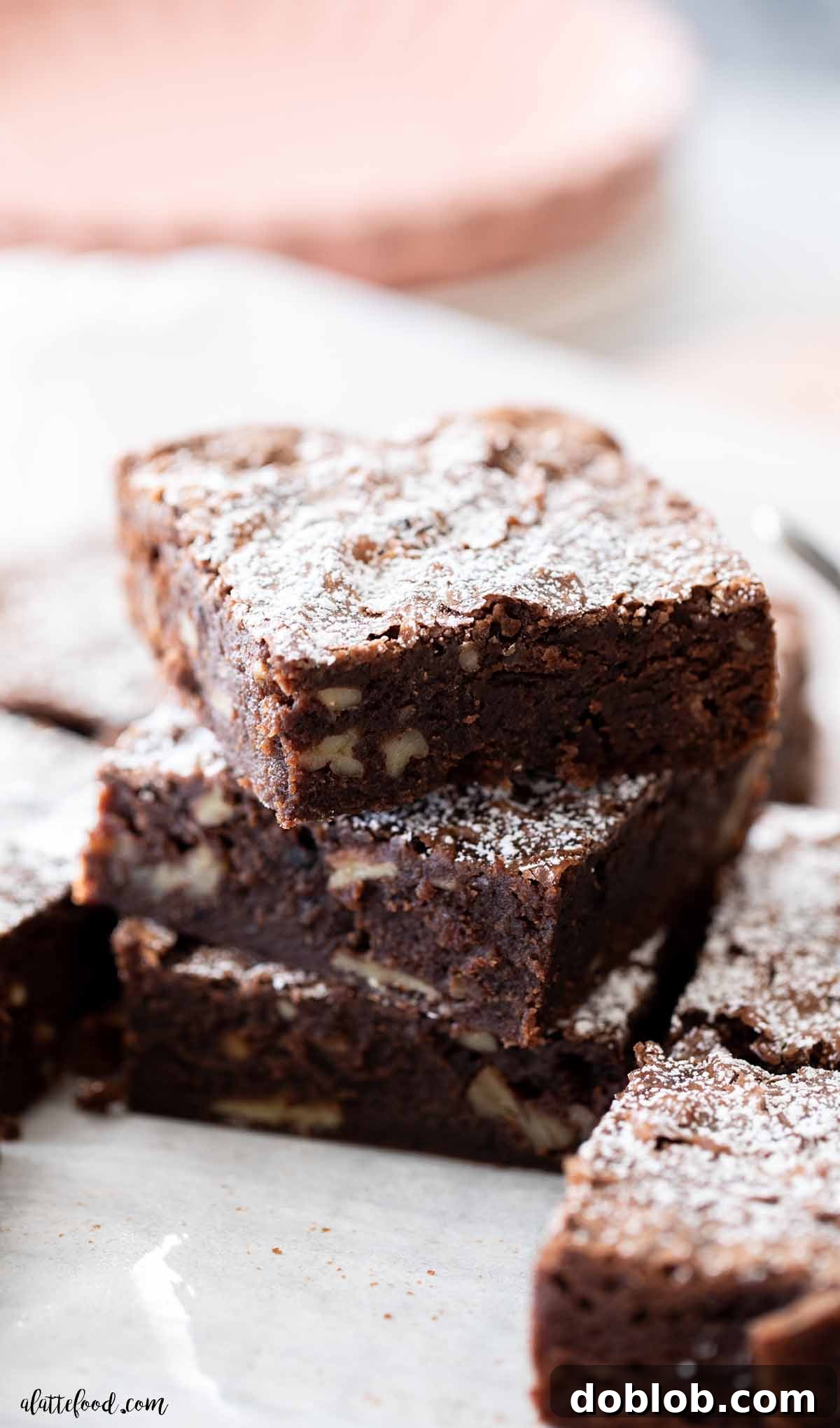 three chocolate fudge cake slices stacked on white parchment paper