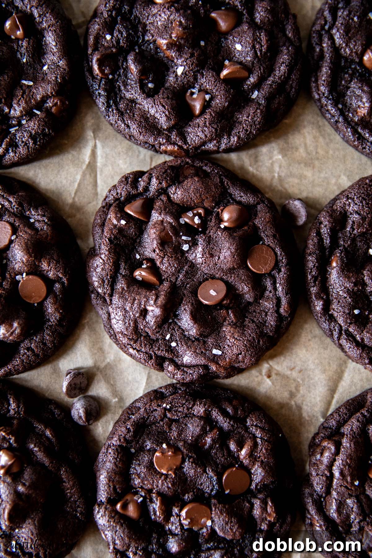 dark chocolate chip cookies with semi-sweet chips and sea salt on brown parchment paper.