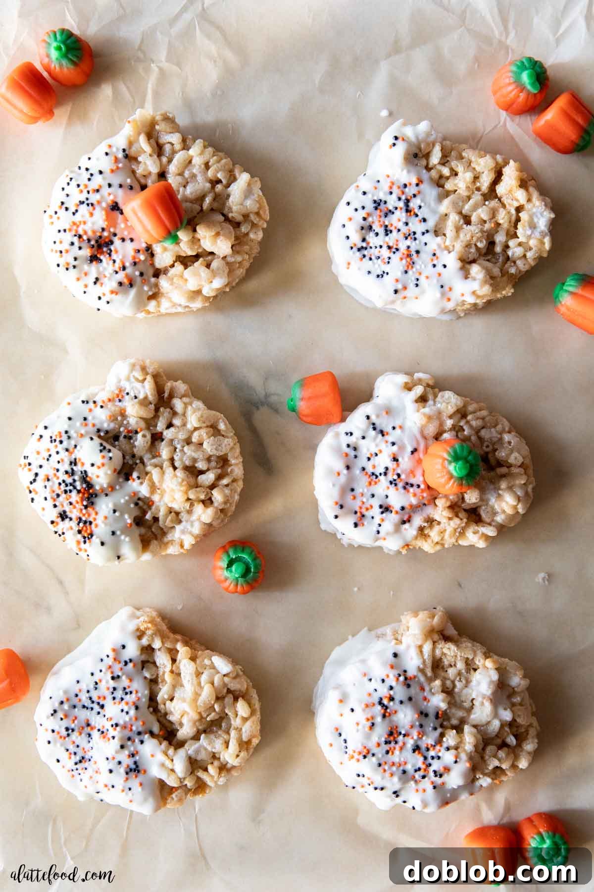Gooey white chocolate dipped pumpkin rice krispie treats, generously spiced with pumpkin pie flavors, resting on brown parchment paper. An irresistible no-bake fall dessert for Halloween and Thanksgiving.