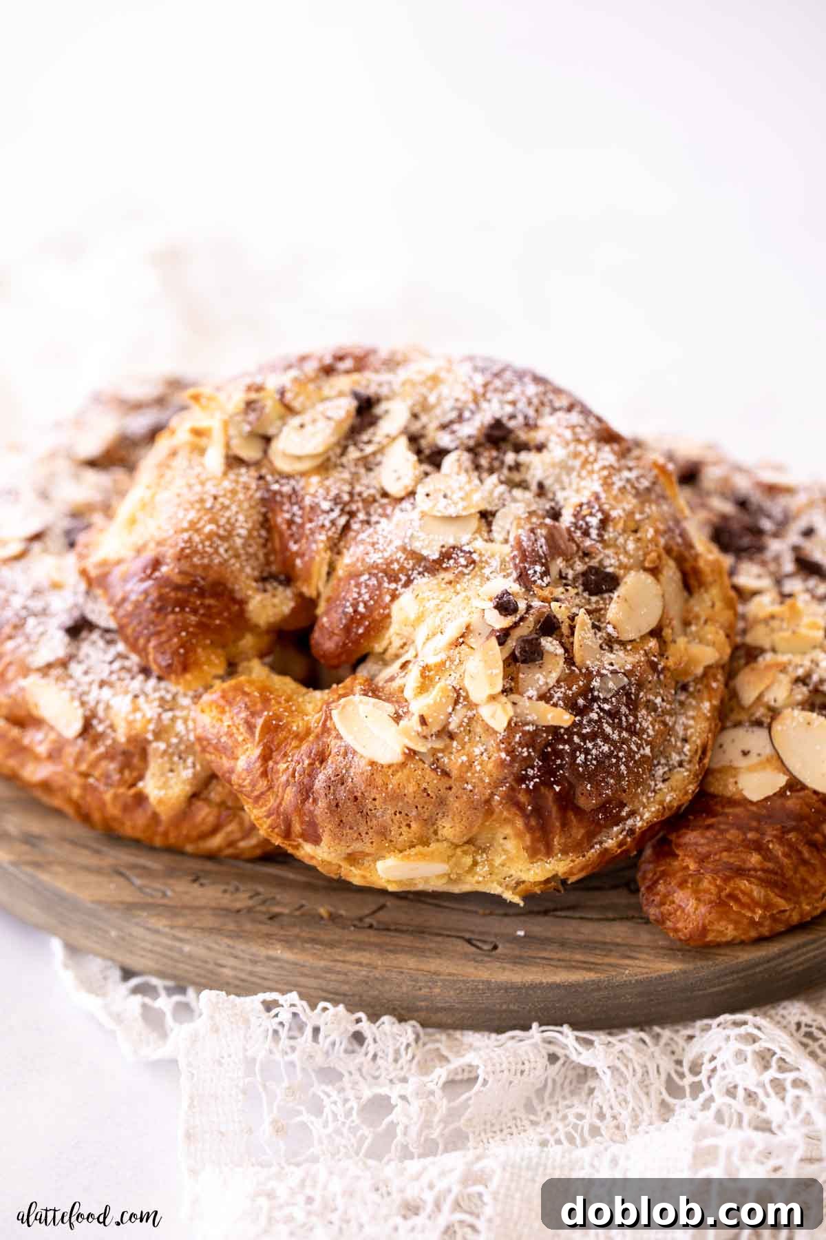 Baked almond croissants with toasted almonds and frangipane on parchment paper.