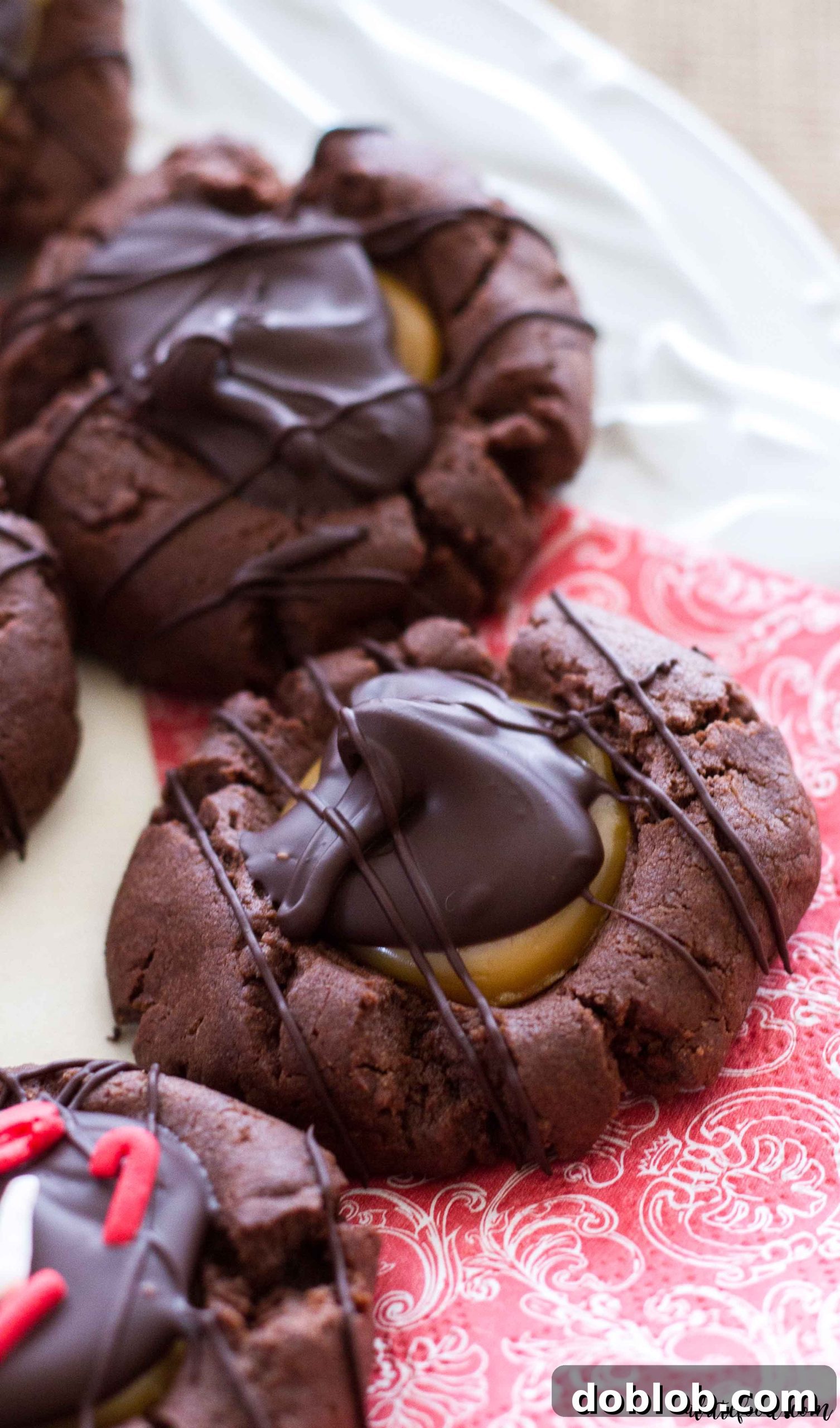 Close-up of golden caramel oozing from the center of a freshly baked chocolate thumbprint cookie.