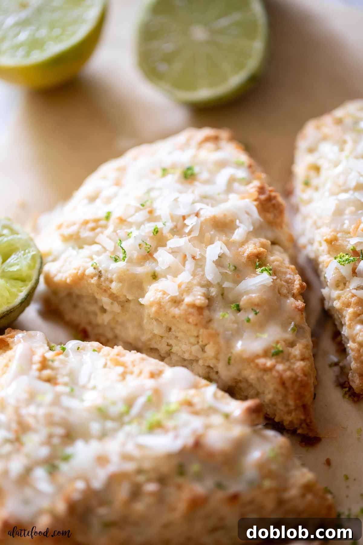 Delicious coconut lime scones with a fresh lime glaze and toasted coconut flakes, beautifully arranged on brown parchment paper.