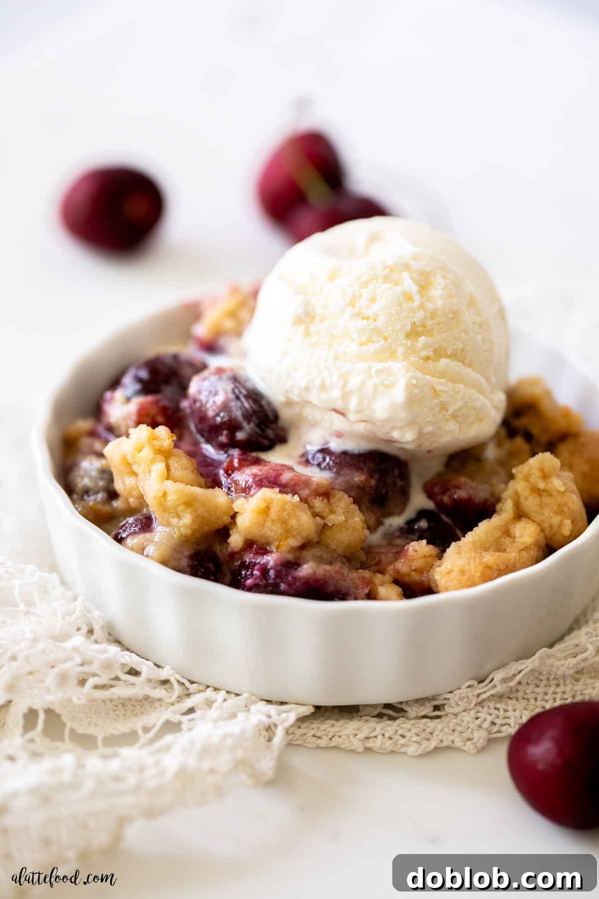 Quick and easy Cherry Crumble with sweet cherries, a crisp buttery topping, and a scoop of vanilla ice cream. Homemade cherry crumble with a shortbread crust in a white bowl with vanilla ice cream on top, ready to eat.