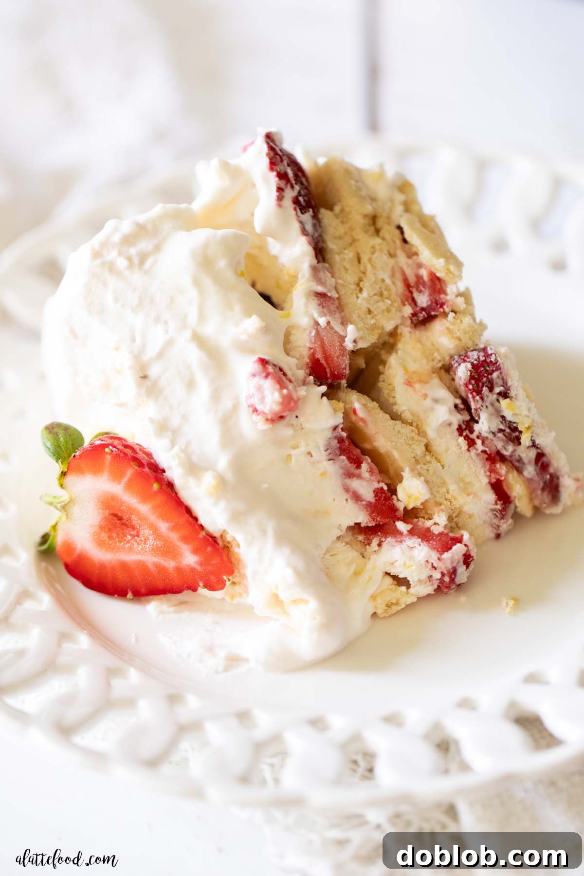 lemon strawberry freezer cake sliced and served on a white plate with scalloped edges.