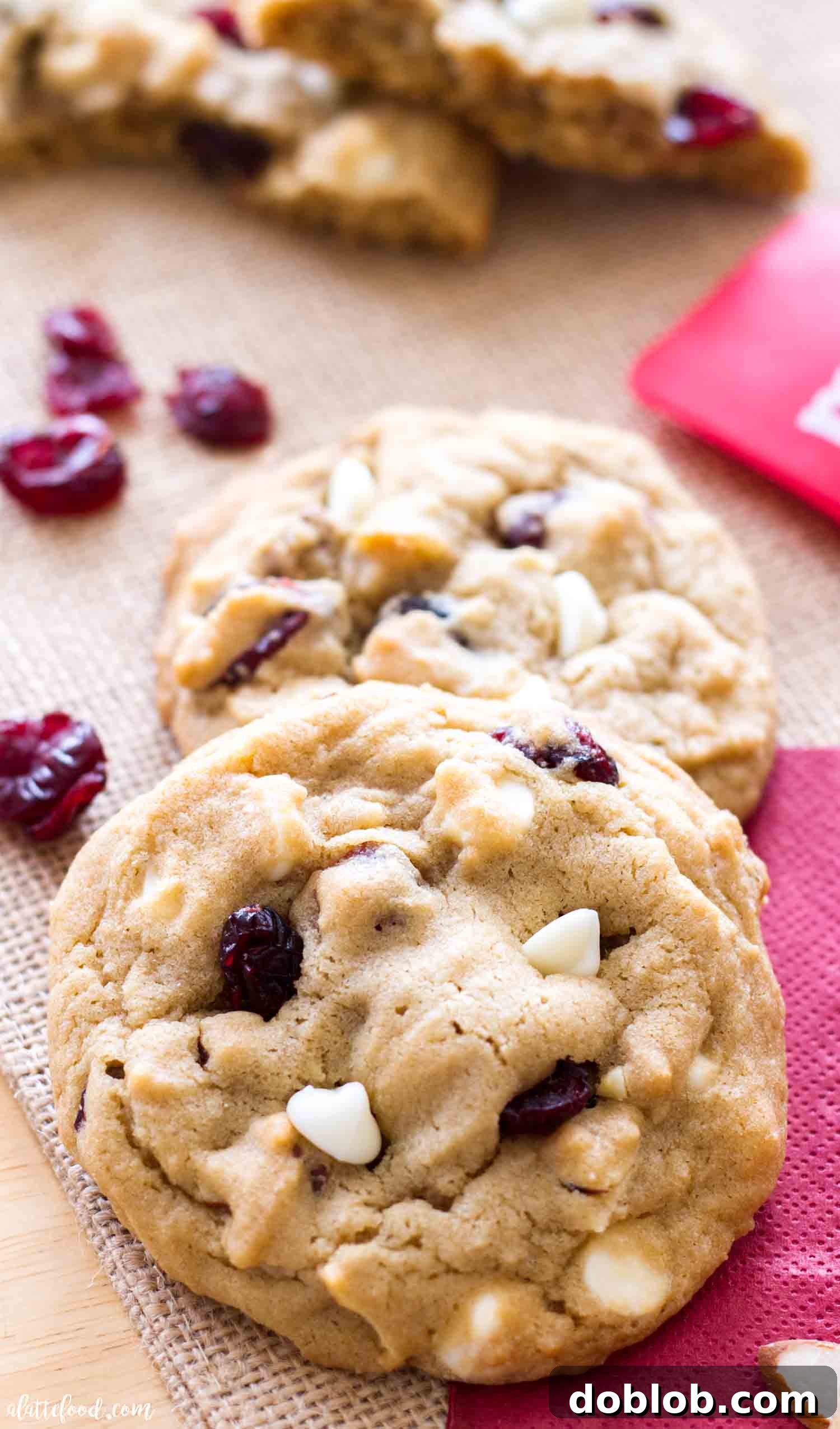 A batch of freshly baked White Chocolate Cherry Almond Cookies on a cooling rack.