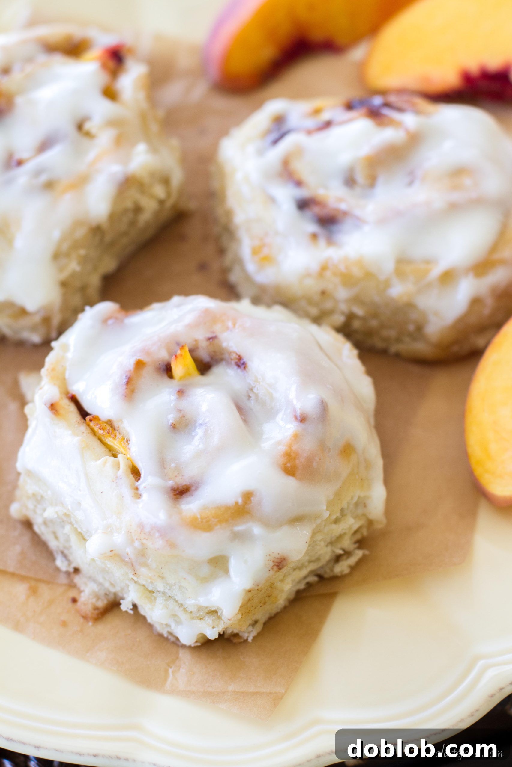 Two warm peach cinnamon rolls coated in a rich cream cheese glaze.