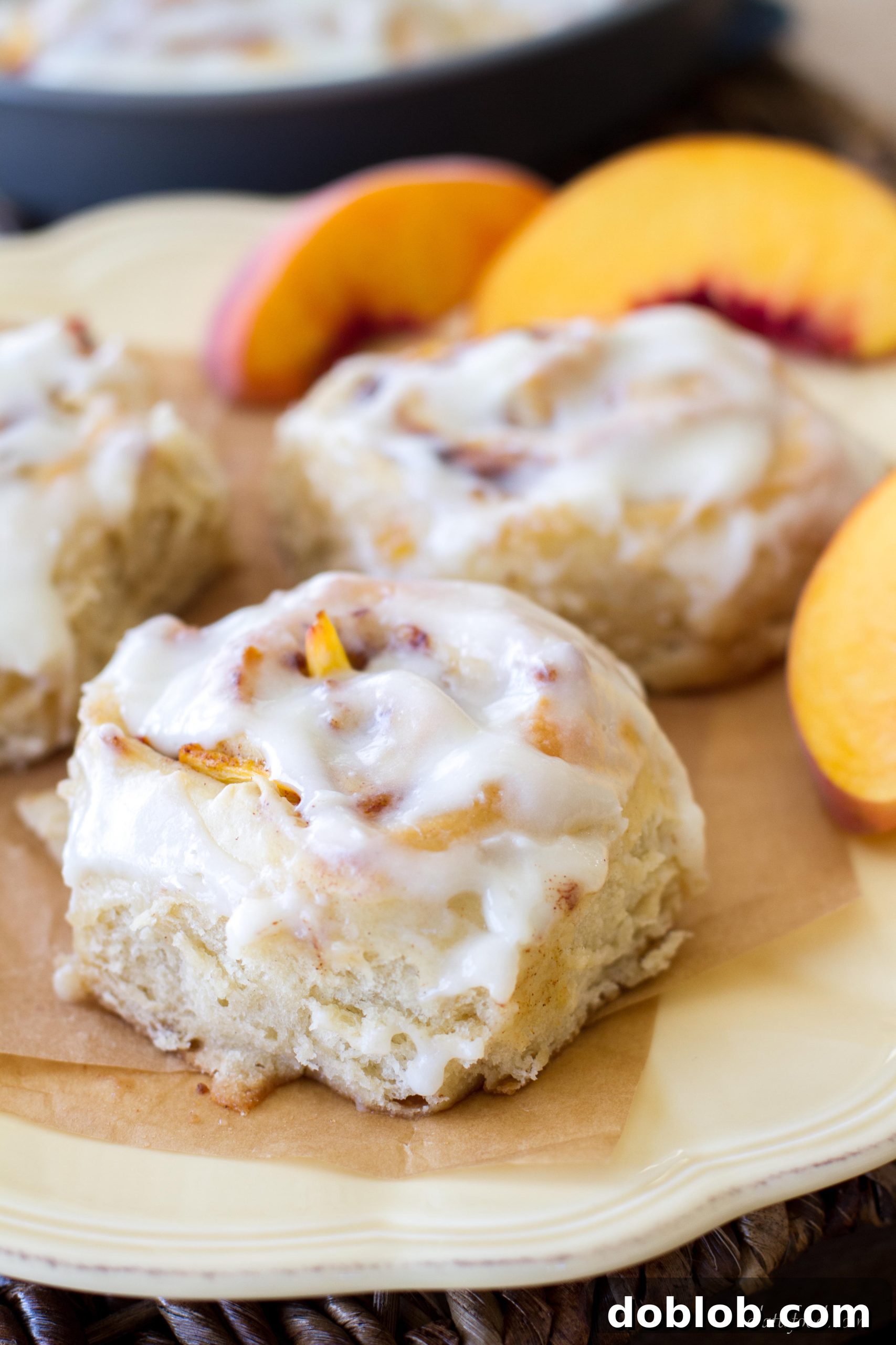 A single peach cinnamon roll with a generous swirl of cream cheese glaze.