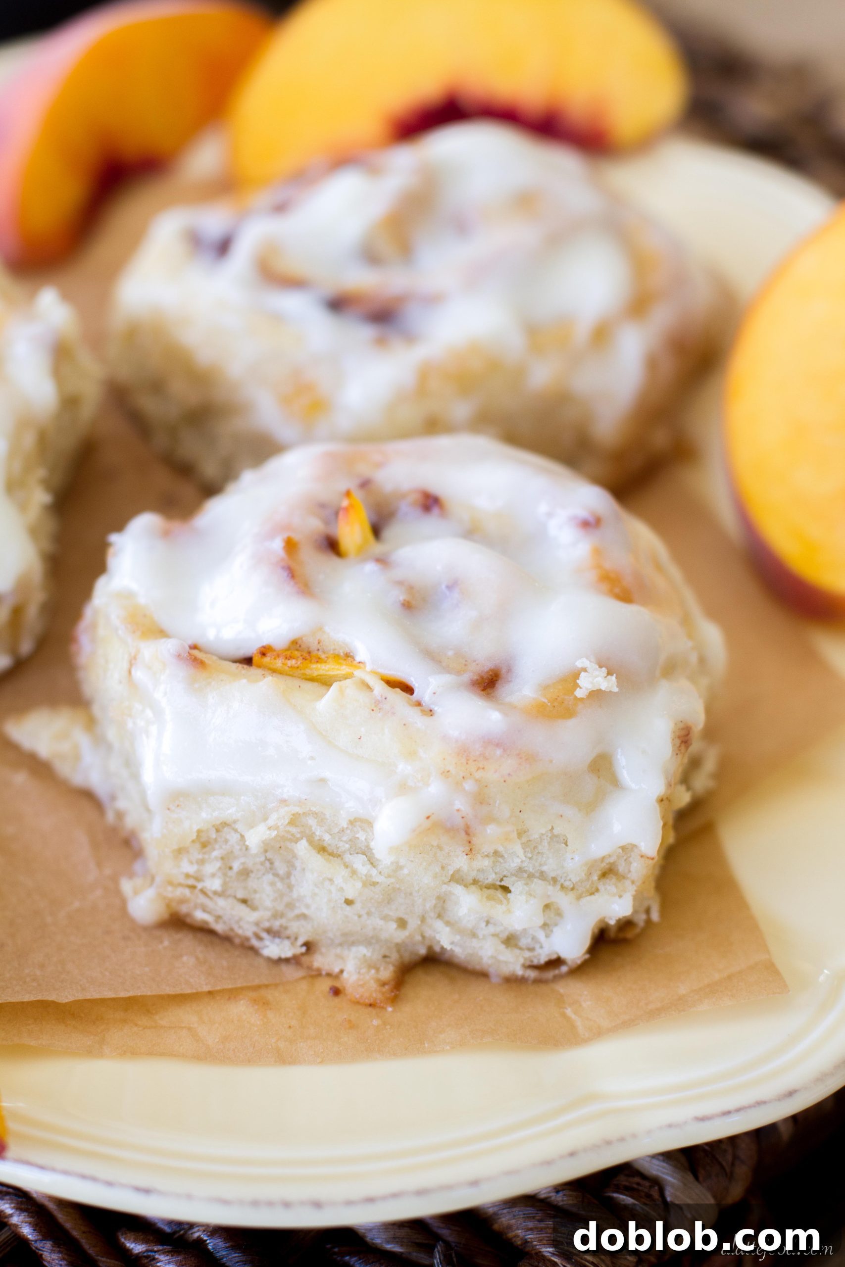A top-down view of peach cinnamon rolls drizzled generously with cream cheese glaze.