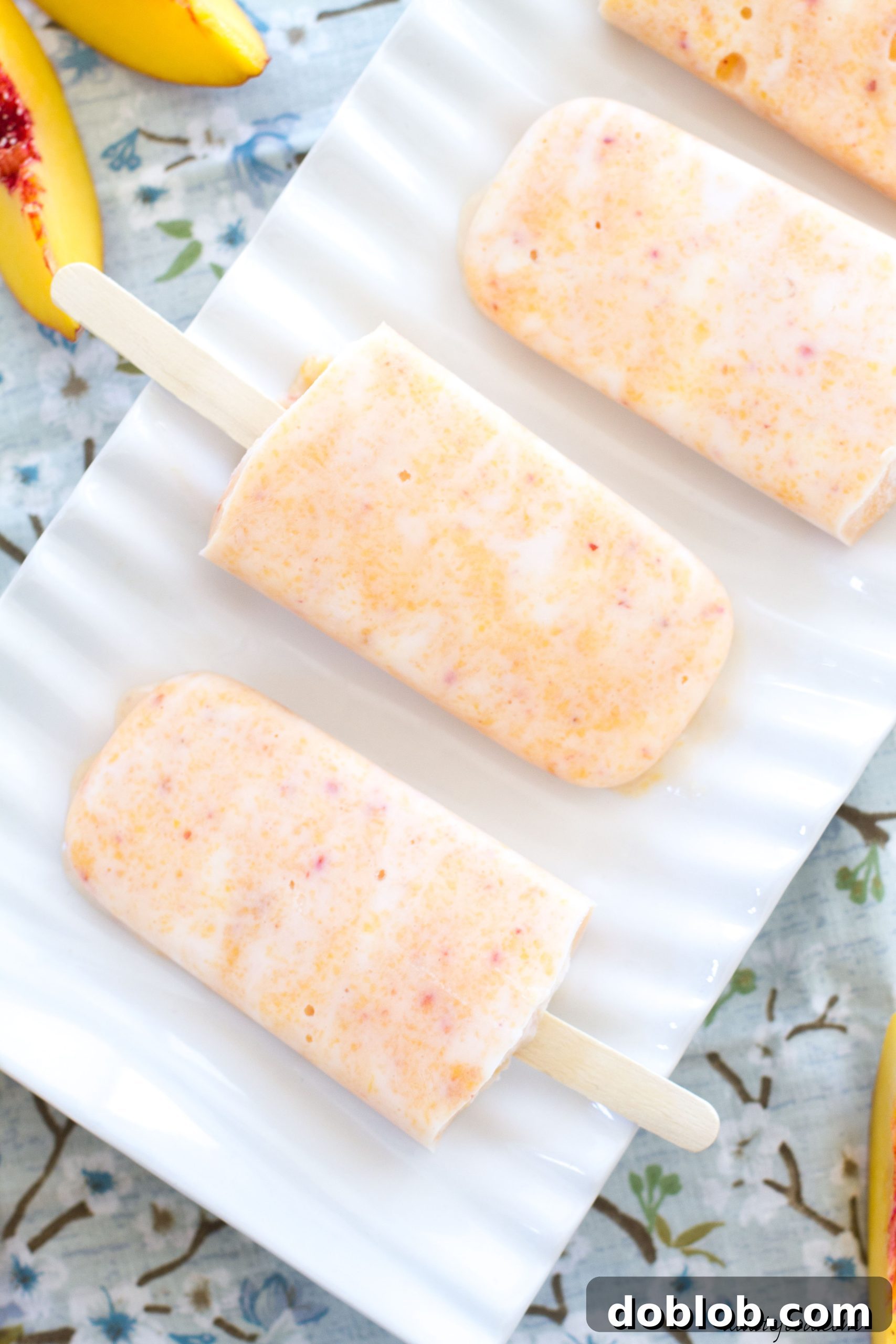 A trio of creamy peach popsicles standing upright, ready to be enjoyed on a hot day