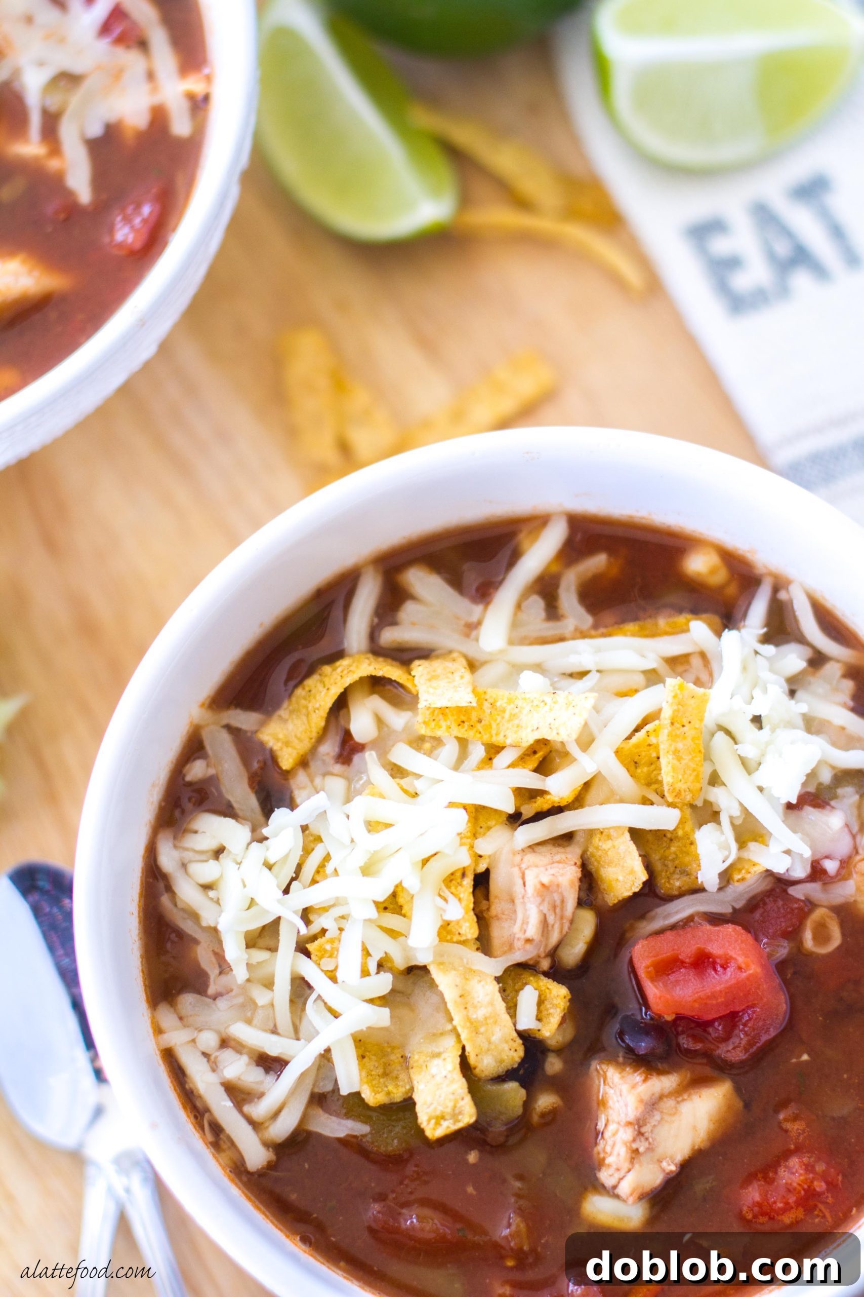 Close-up of hearty chicken tortilla soup with visible chicken, corn, and black beans.