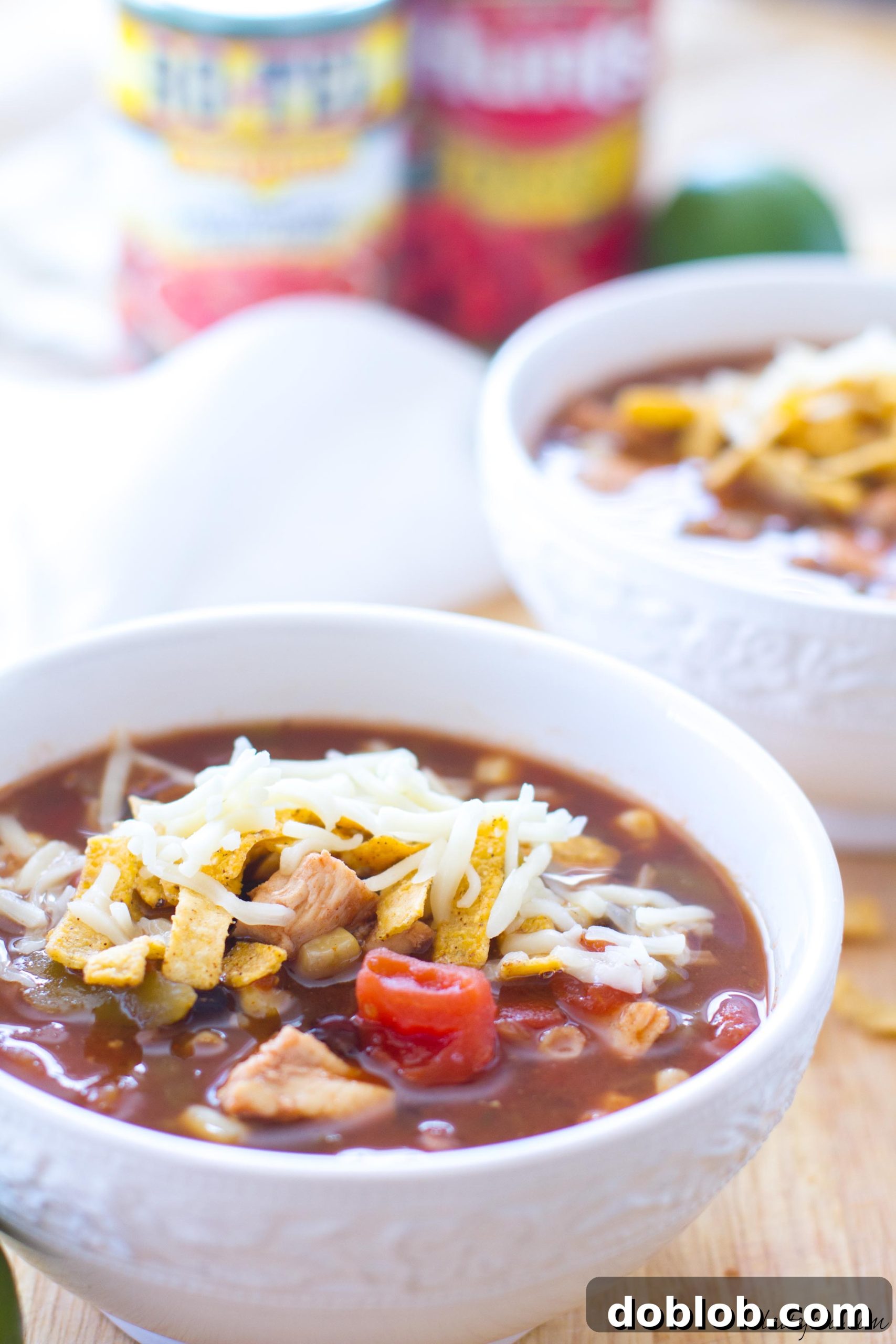 A rustic bowl of chicken tortilla soup garnished with cilantro and lime wedges.