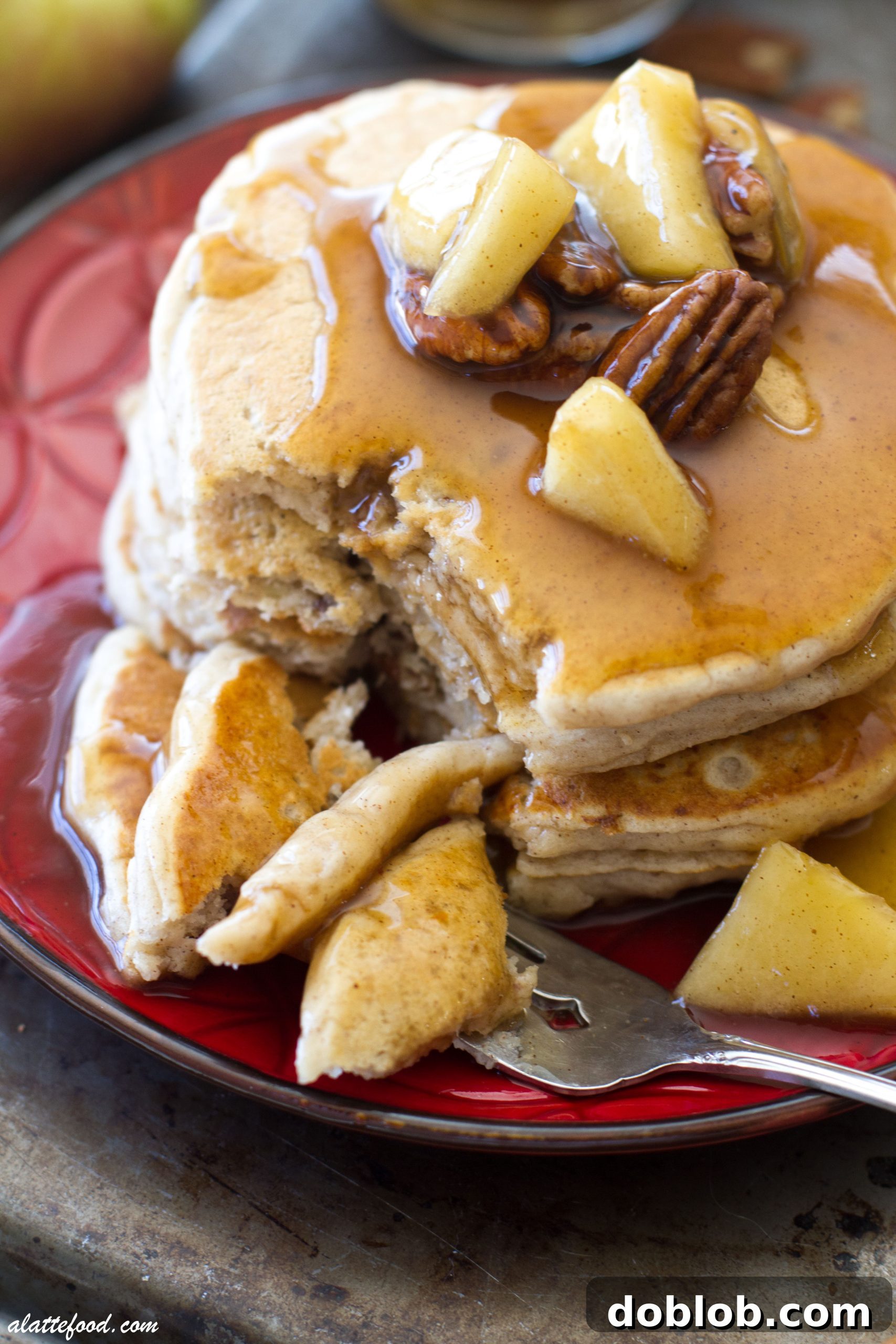 Close-up of a stack of fluffy pecan pie pancakes, glistening with apple cinnamon syrup.