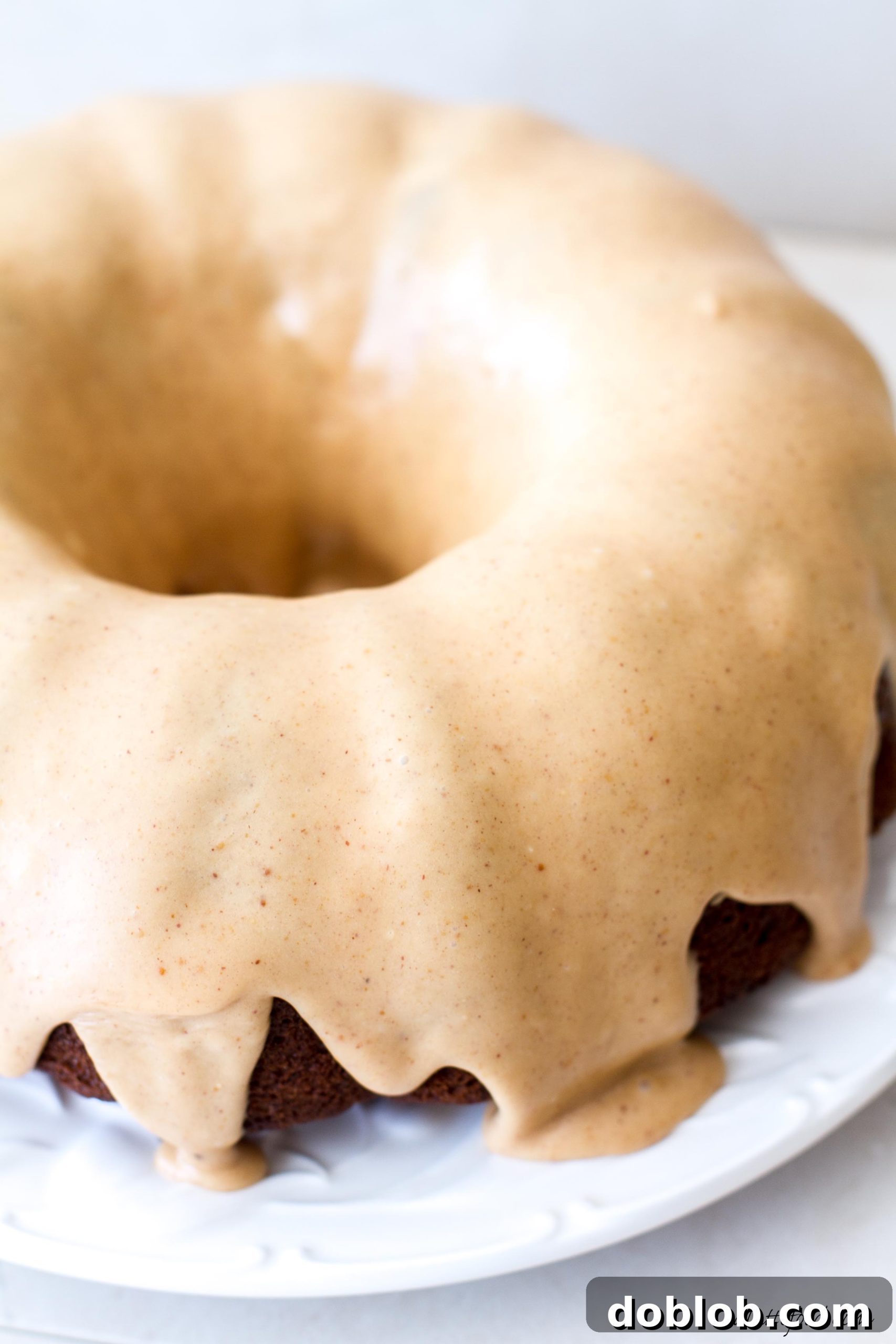 Peanut Butter Drizzled Banana Bundt Dream 6 Full view of the banana bundt cake with peanut butter glaze on a wooden board with a cake stand, ready for serving.