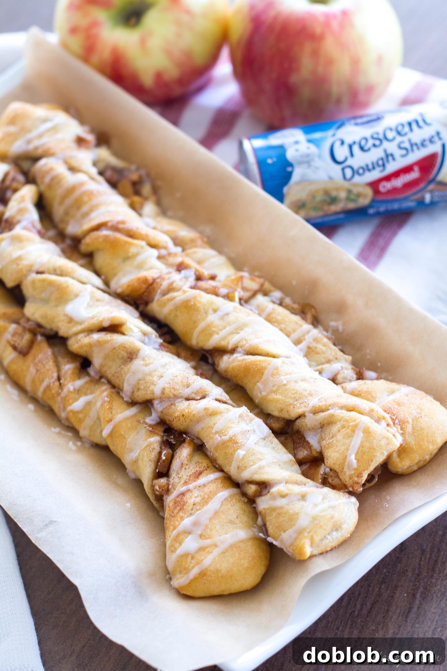 A beautifully baked apple danish twist on a white plate, showcasing the golden crust and glaze