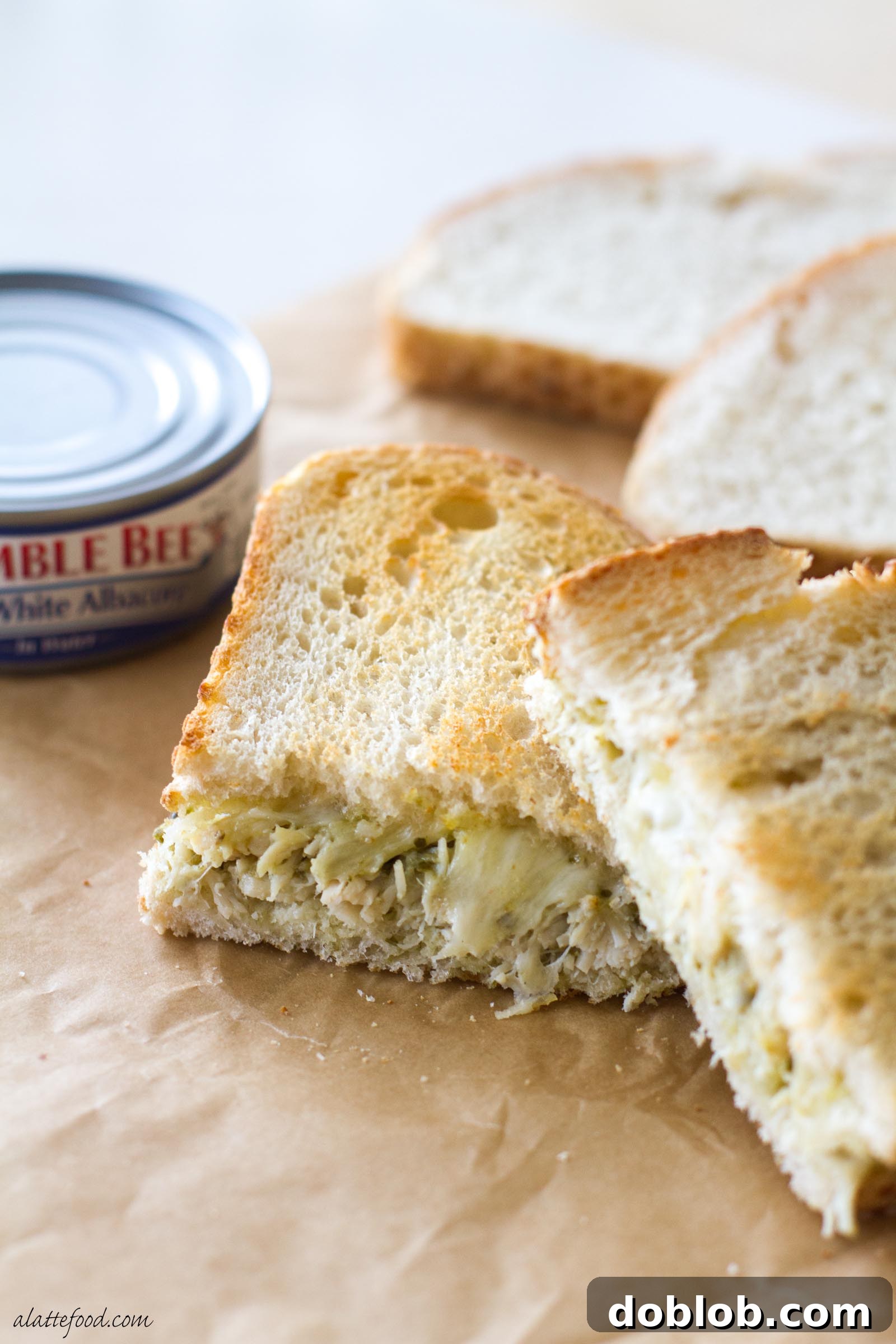 A stacked view of two pesto tuna grilled cheese halves, highlighting the crispy sourdough bread and generous, flavorful filling.