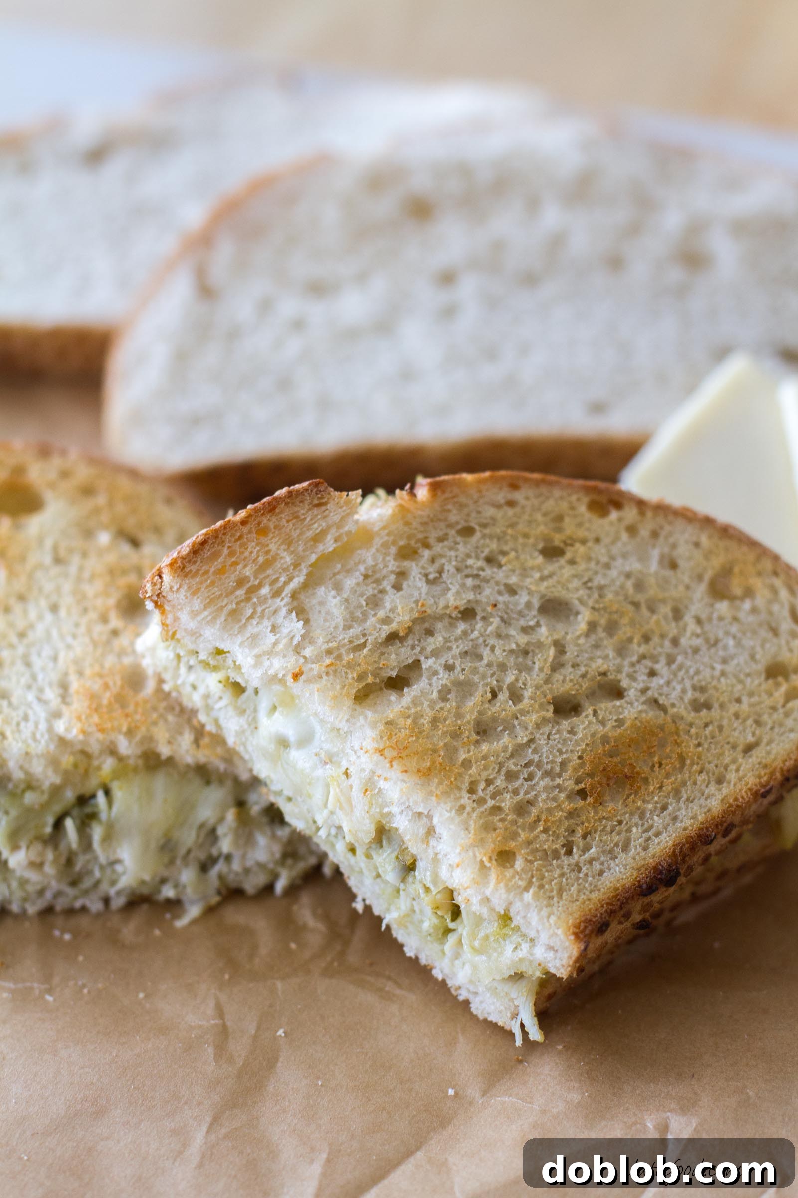 A close-up of the grilled cheese sandwich on a cutting board, ready to be sliced, emphasizing the perfectly toasted bread.