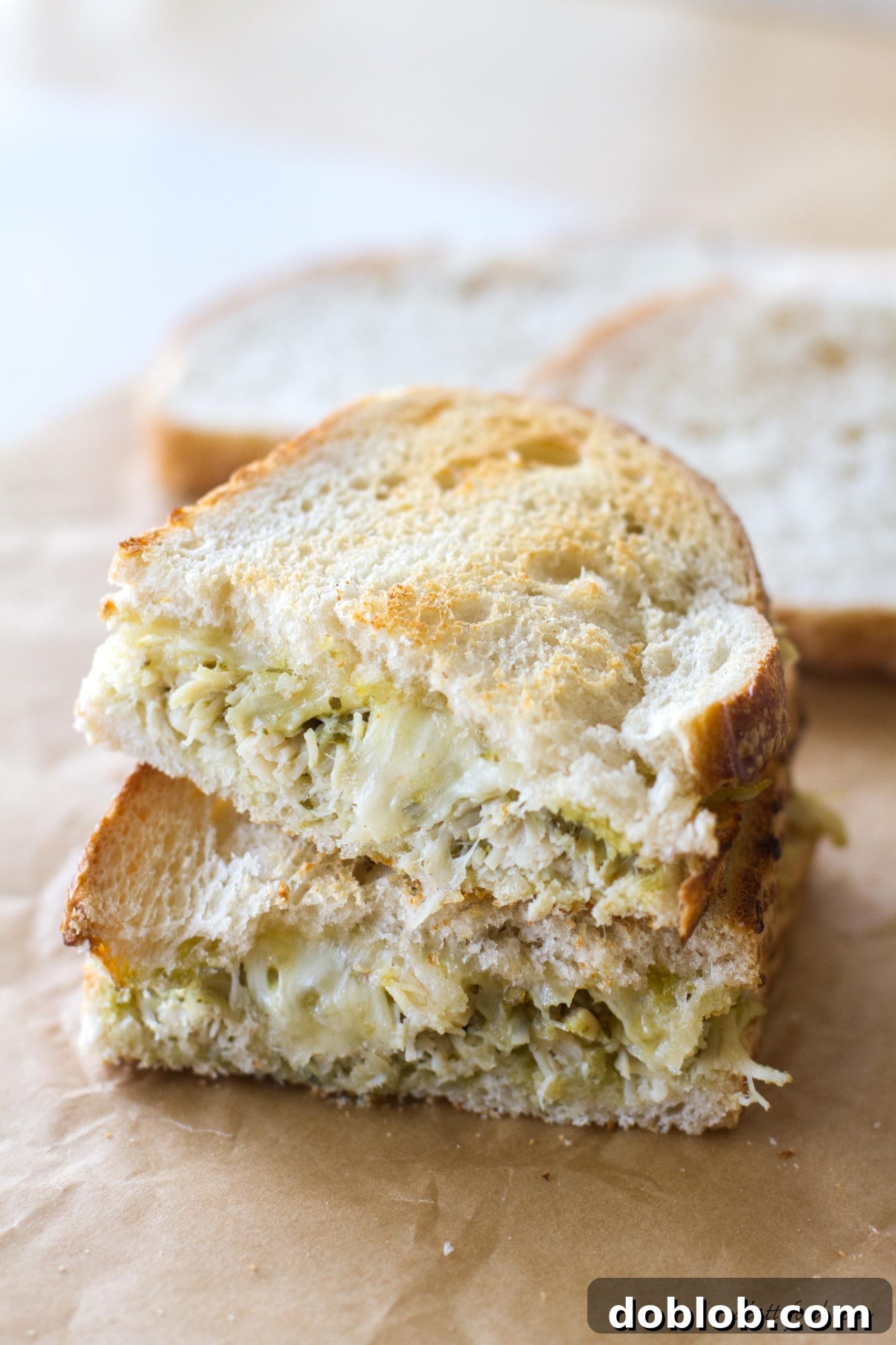 Gourmet Pesto Tuna Melt 7 A vibrant, stylized shot of a whole pesto tuna grilled cheese sandwich on a light background, emphasizing its gourmet appeal.