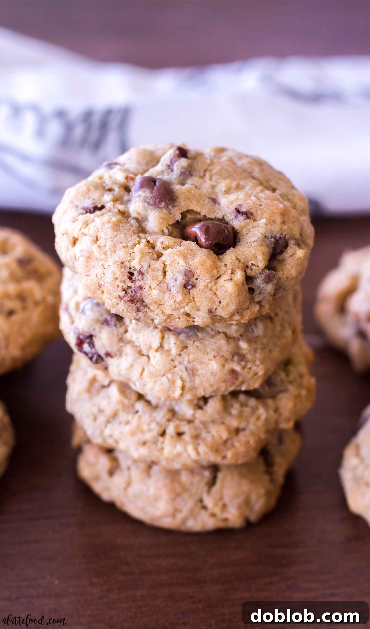 Stack of oatmeal chocolate covered raisin cookies on a wooden surface, ready to be enjoyed.