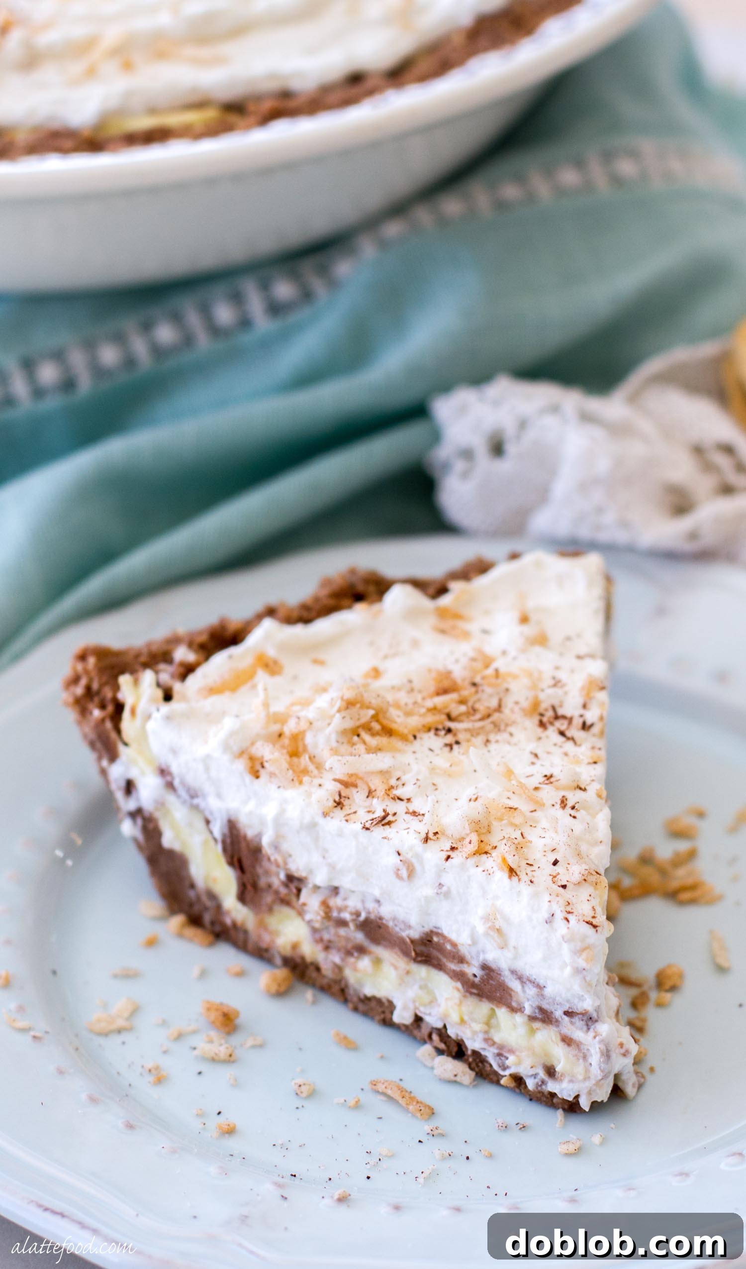 A whole no-bake chocolate coconut cream pie, topped with a generous layer of whipped cream, toasted coconut, and chocolate shavings, ready to be sliced.