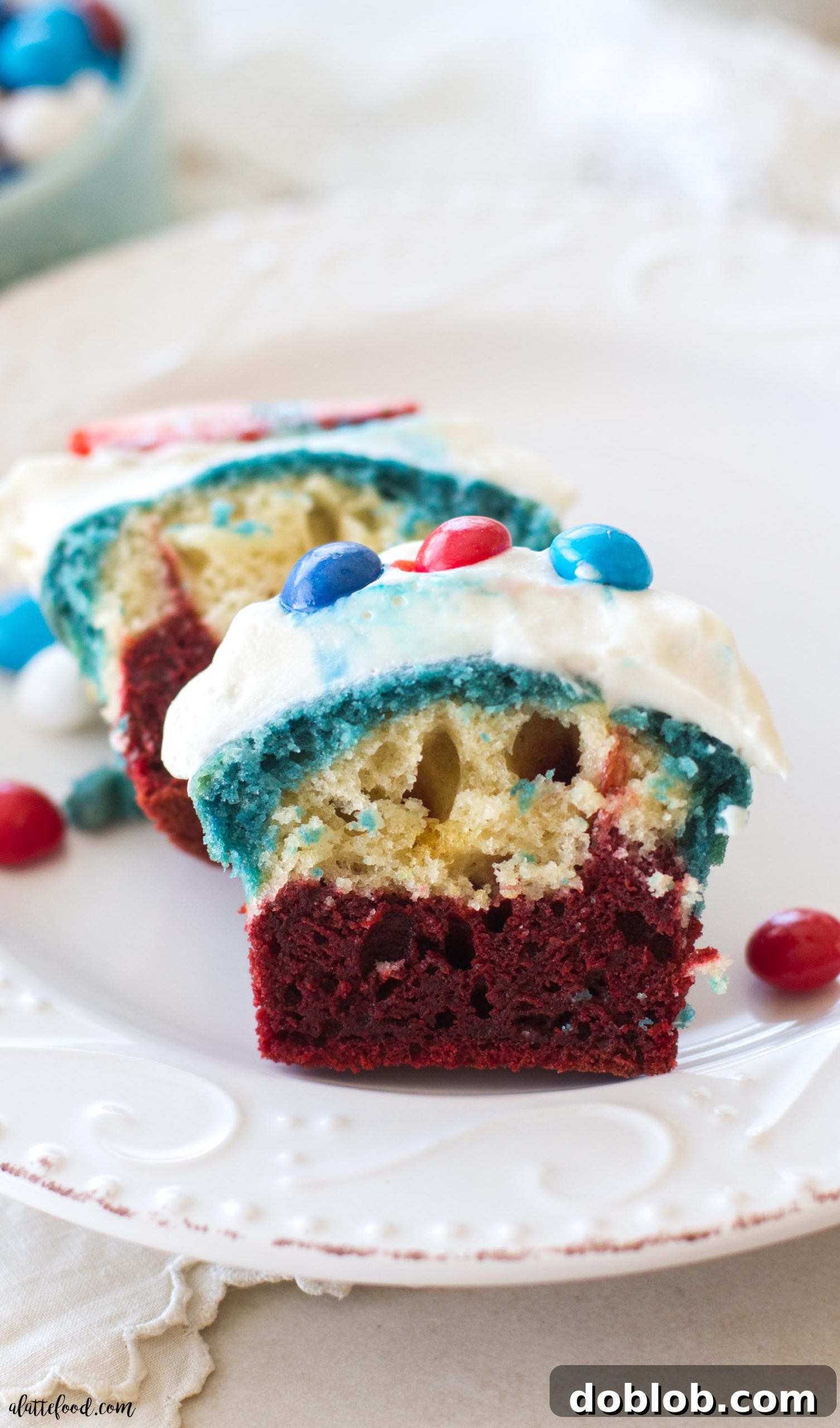 A top-down shot of a single red, white, and blue velvet cupcake with cream cheese frosting and patriotic toppings.