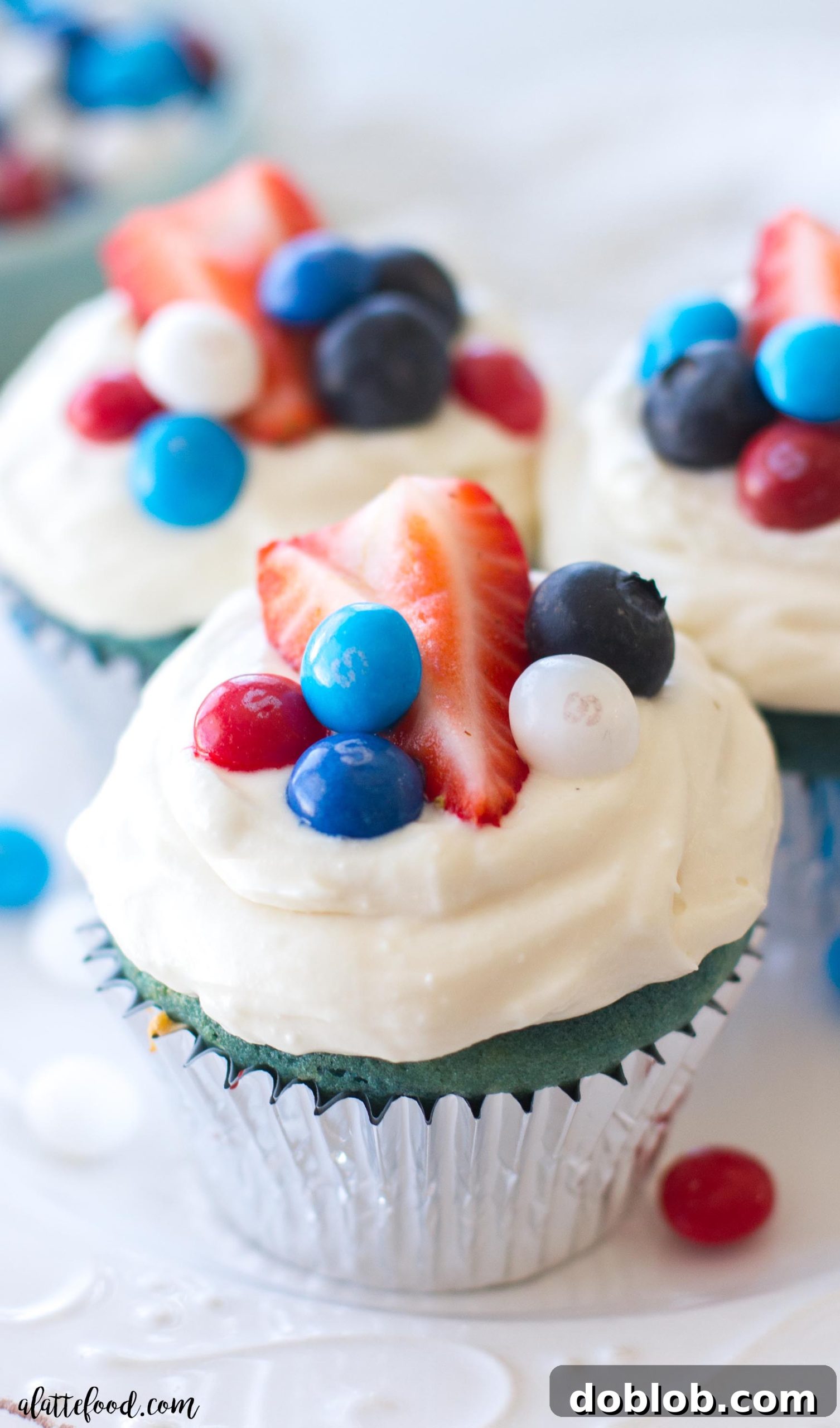 Two red, white, and blue velvet cupcakes showcased on a wooden surface, ready for a summer celebration.