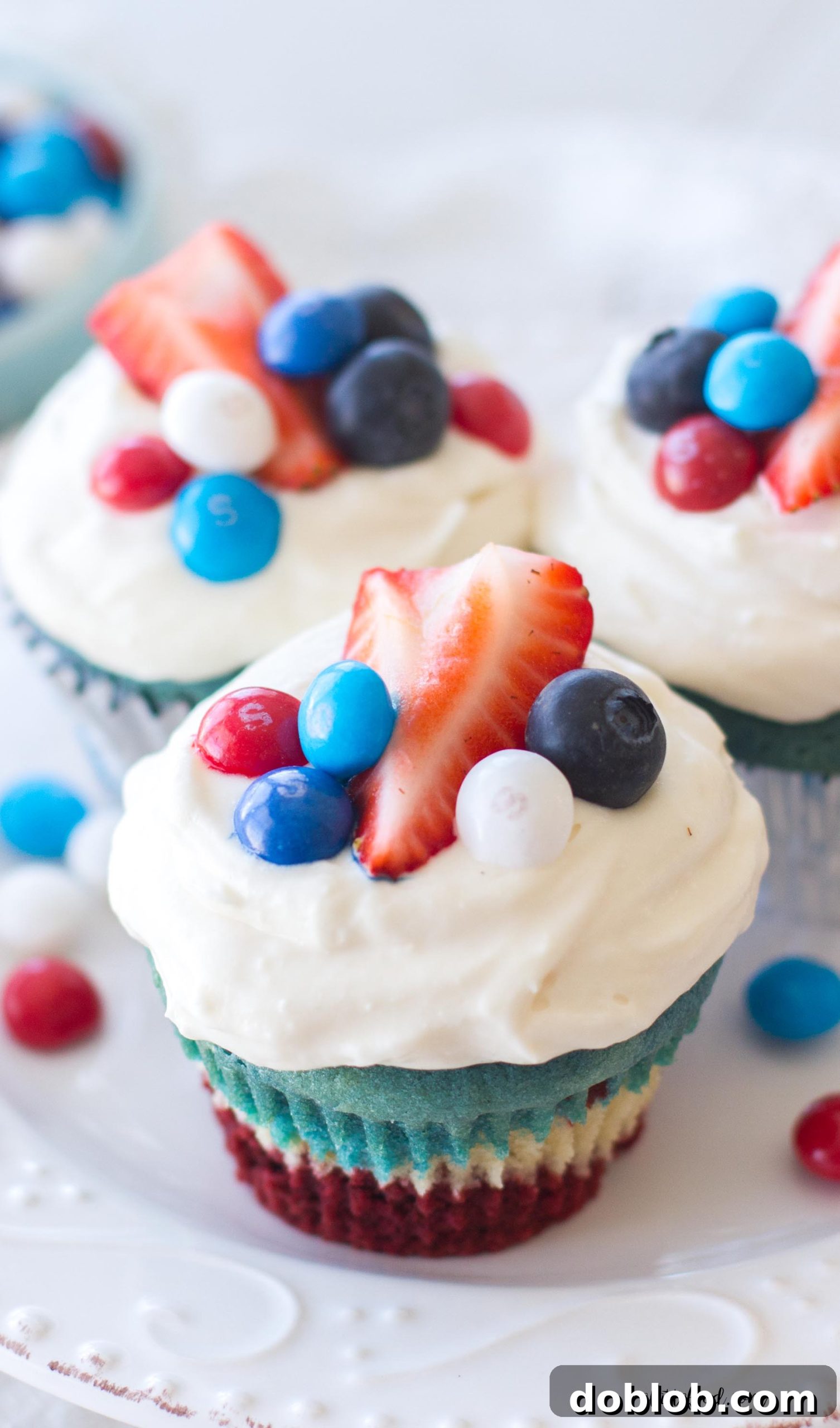 A large tray of red, white, and blue velvet cupcakes cooling on a wire rack.