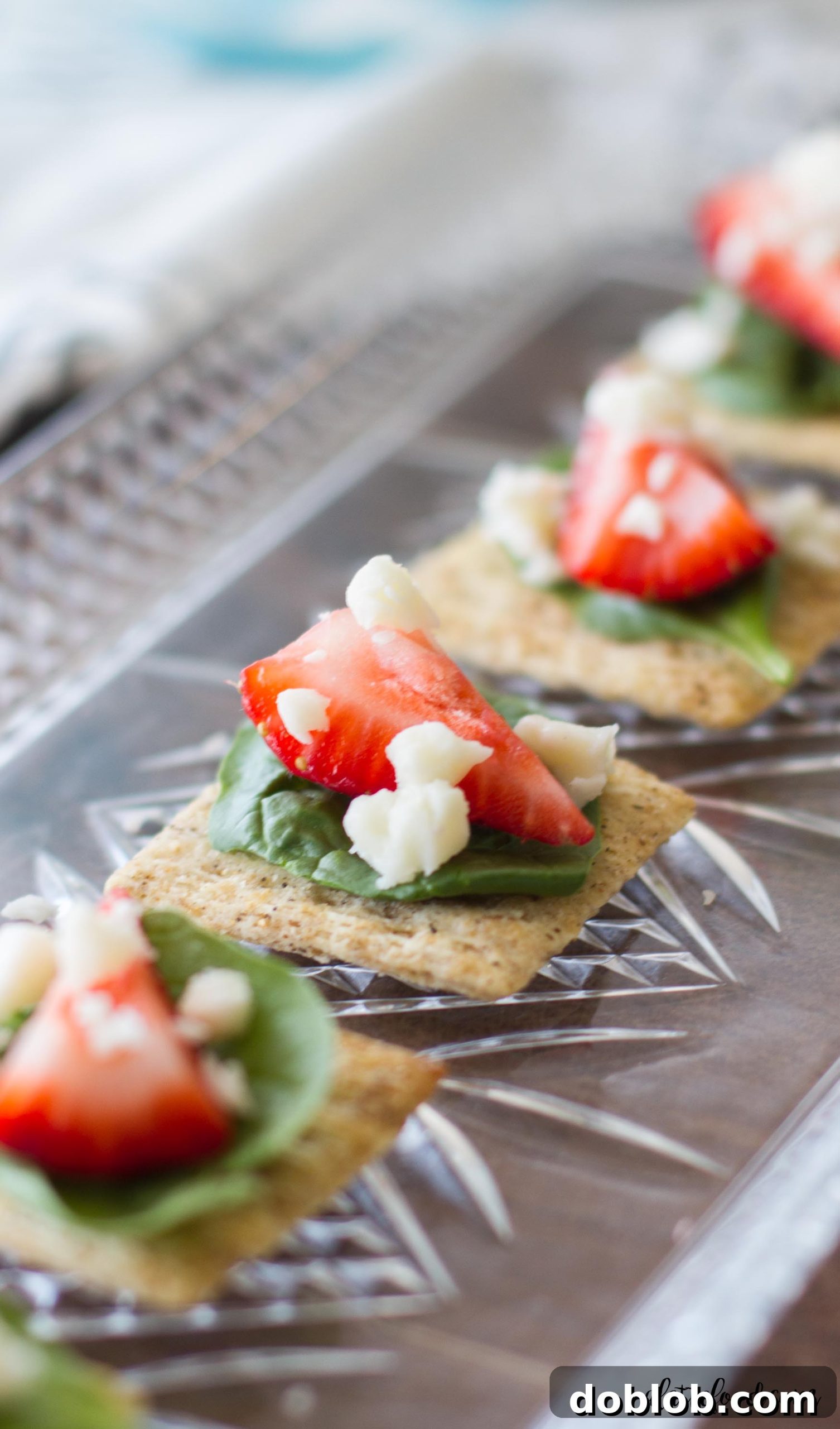 An array of beautifully arranged Spinach, Strawberry, and Feta TRISCUIT appetizers on a serving tray, ready for guests.