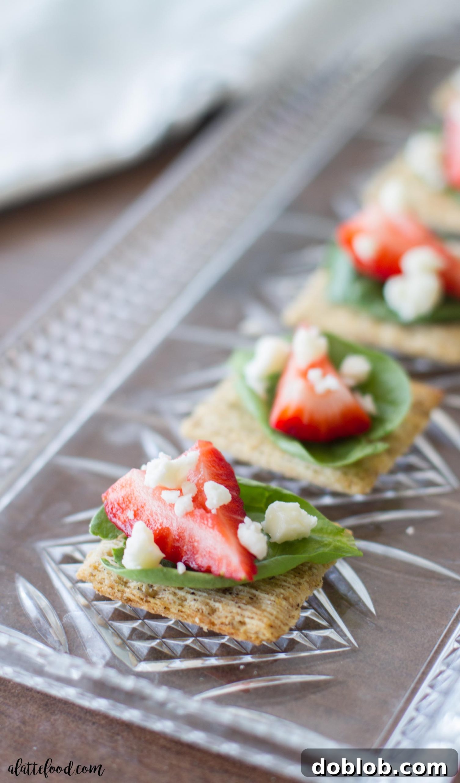 A visually appealing shot of the completed Spinach, Strawberry, and Feta TRISCUIT appetizers on a white plate.