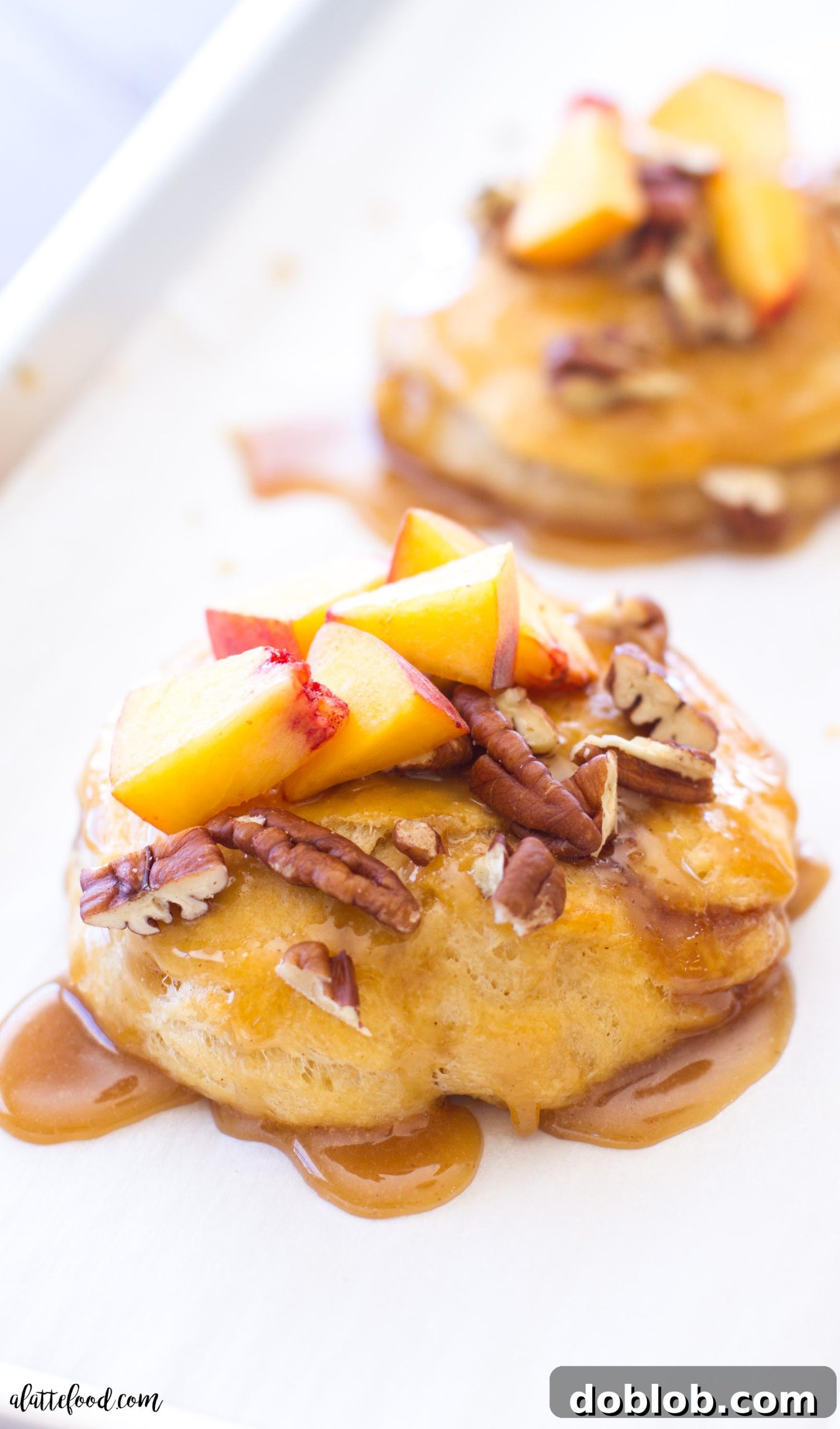 Freshly baked peach pecan sticky buns cooling on a wire rack, drizzled with caramel sauce.