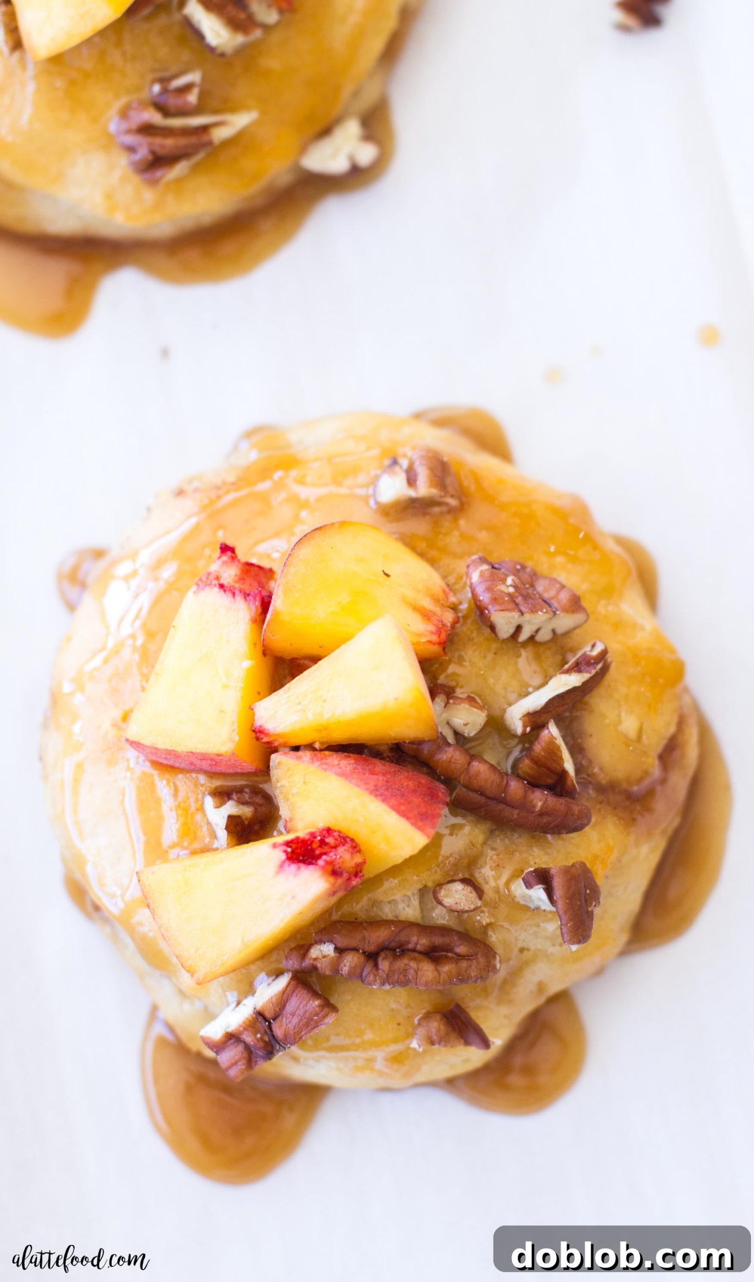A serving of peach pecan sticky buns on a plate, showing the gooey caramel and chopped nuts.