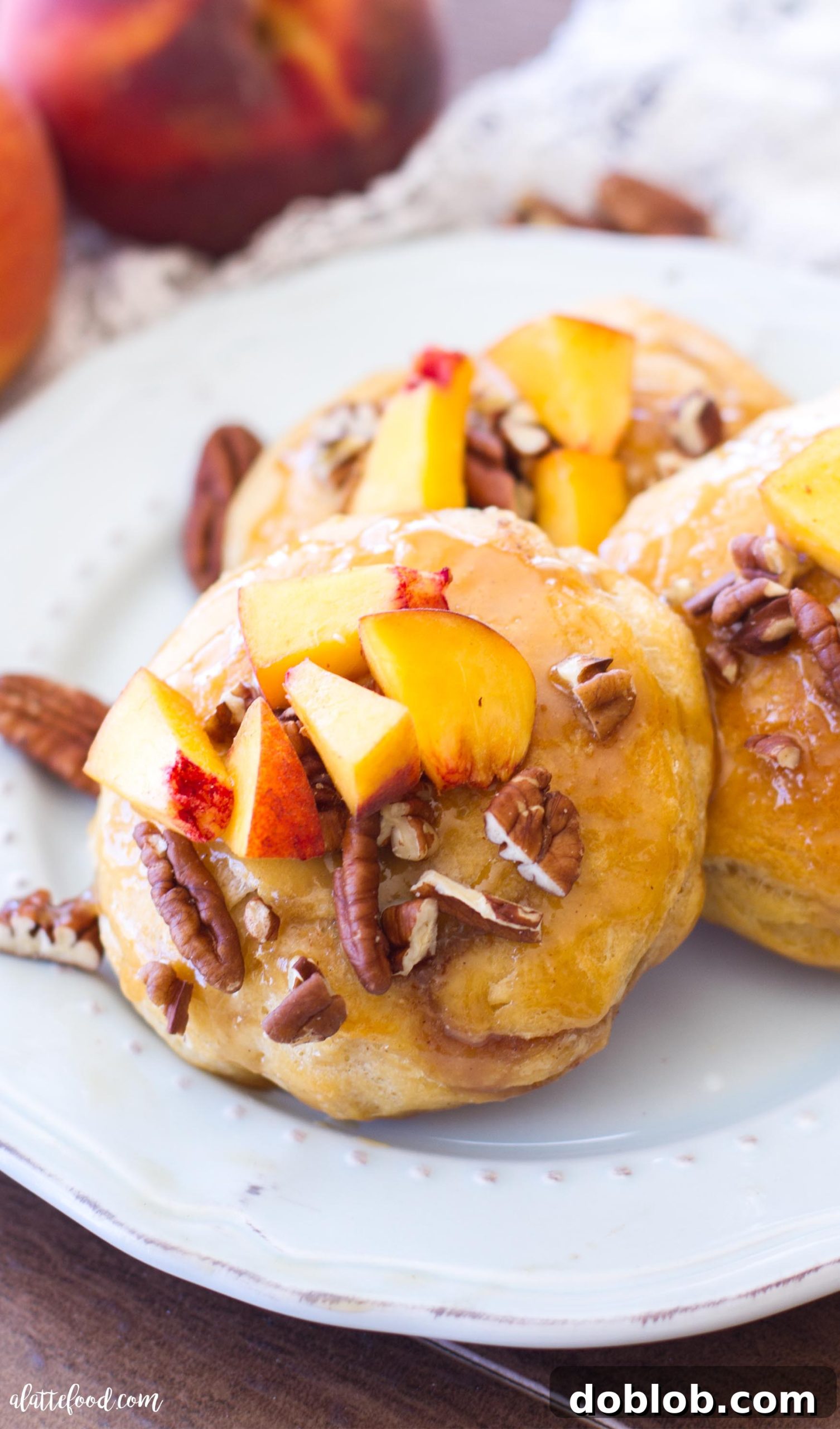 A close-up shot of a single peach pecan sticky bun, showing off the perfectly baked biscuit and generous caramel drizzle.