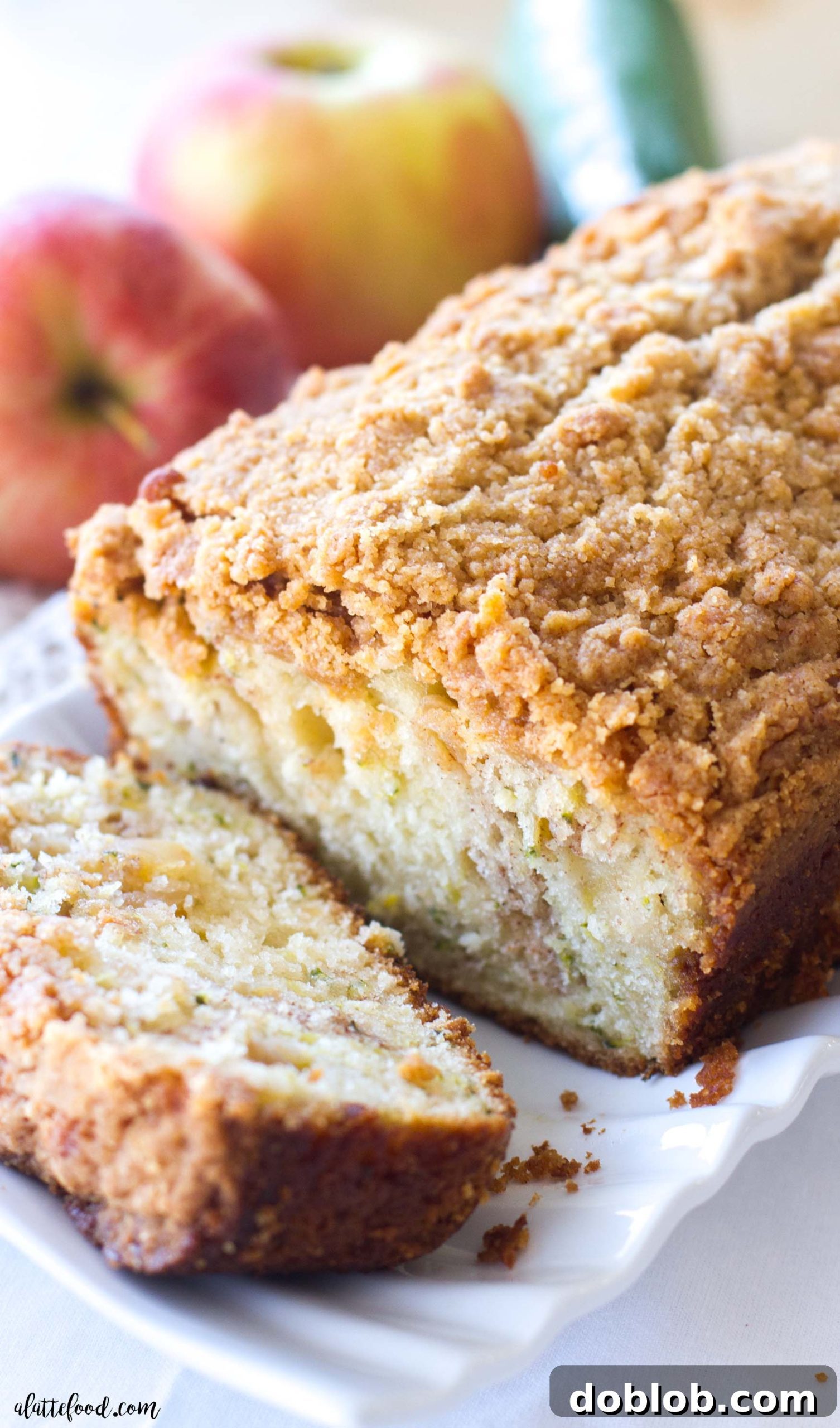 A beautifully sliced piece of Zucchini Apple Crumb Bread, showing the fluffy interior, apple chunks, and a thick layer of crumb topping.