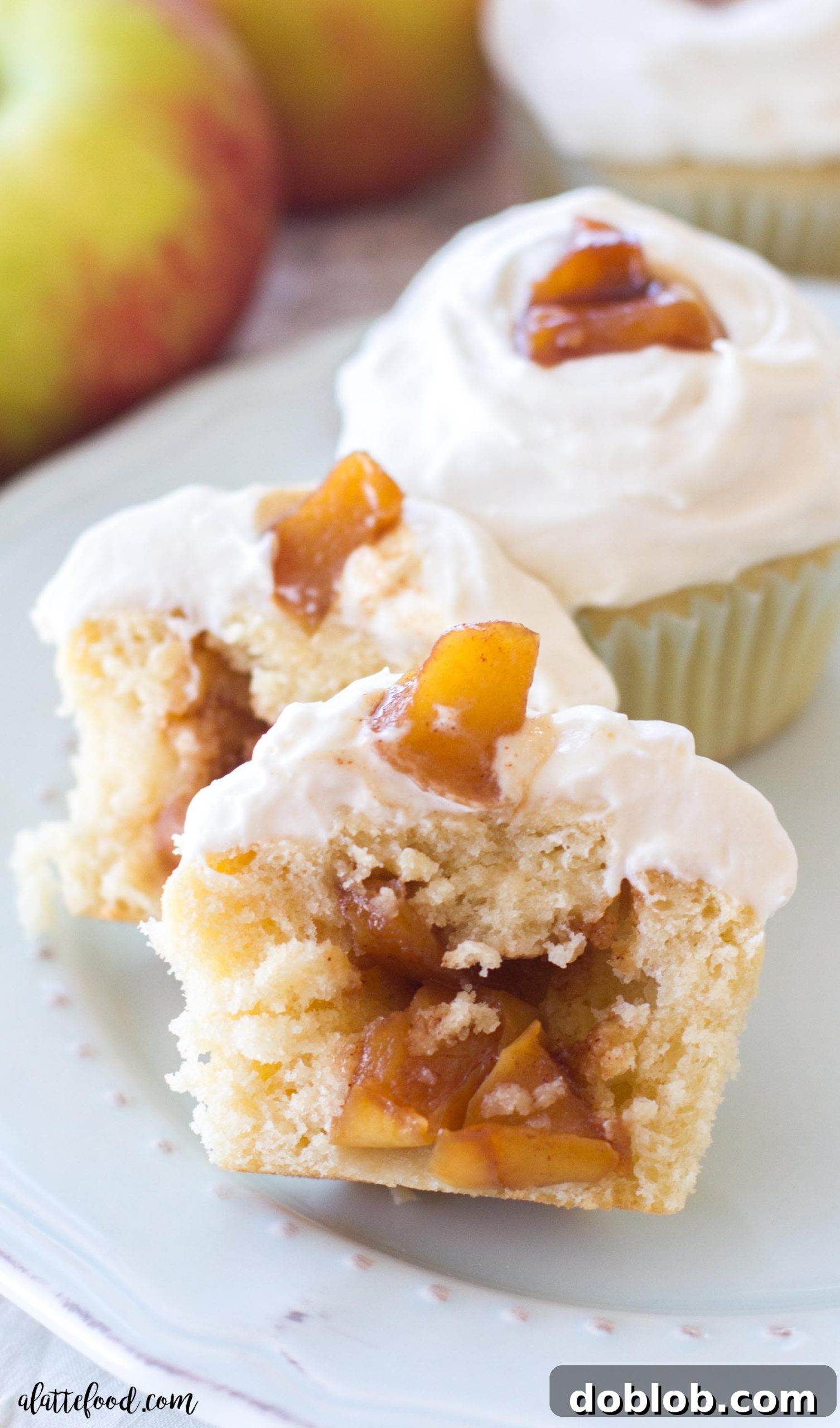 Spiced Apple Delights 3 Close-up of a freshly baked apple pie cupcake, showcasing its golden-brown cake, rich apple filling, and elegant frosting swirl.