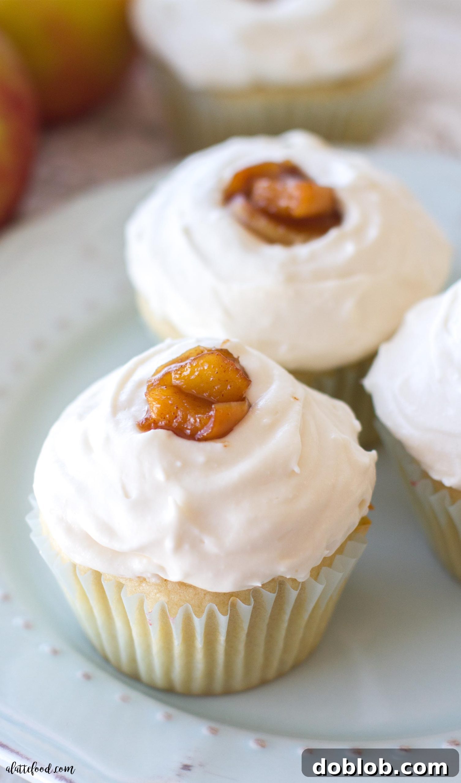 Spiced Apple Delights 5 Hand holding an apple pie cupcake, showing the perfect bite of cake, apple filling, and whipped cream frosting.