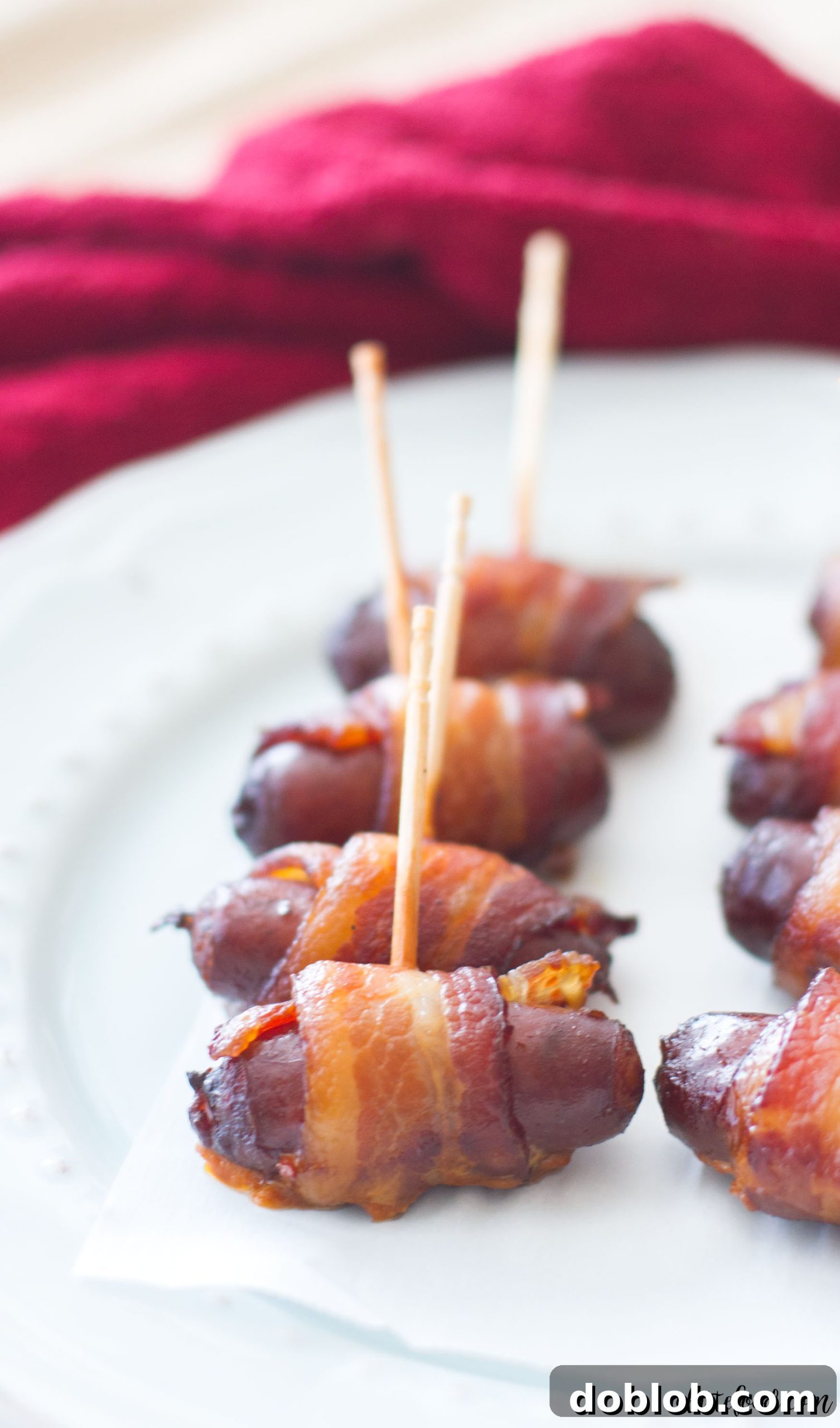 A delicious single Slow Cooker Peach Barbecue Bacon Wrapped Smokie on a white plate, showcasing the crispy bacon.