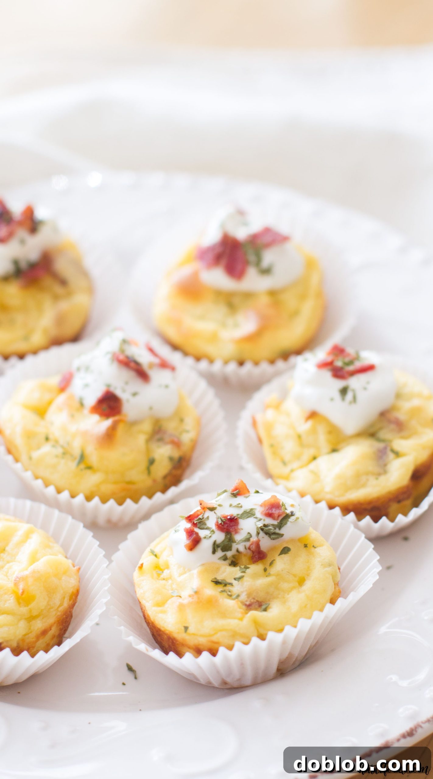 A vibrant overhead shot of freshly baked mashed potato puffs, generously garnished with green chives and red bacon bits.