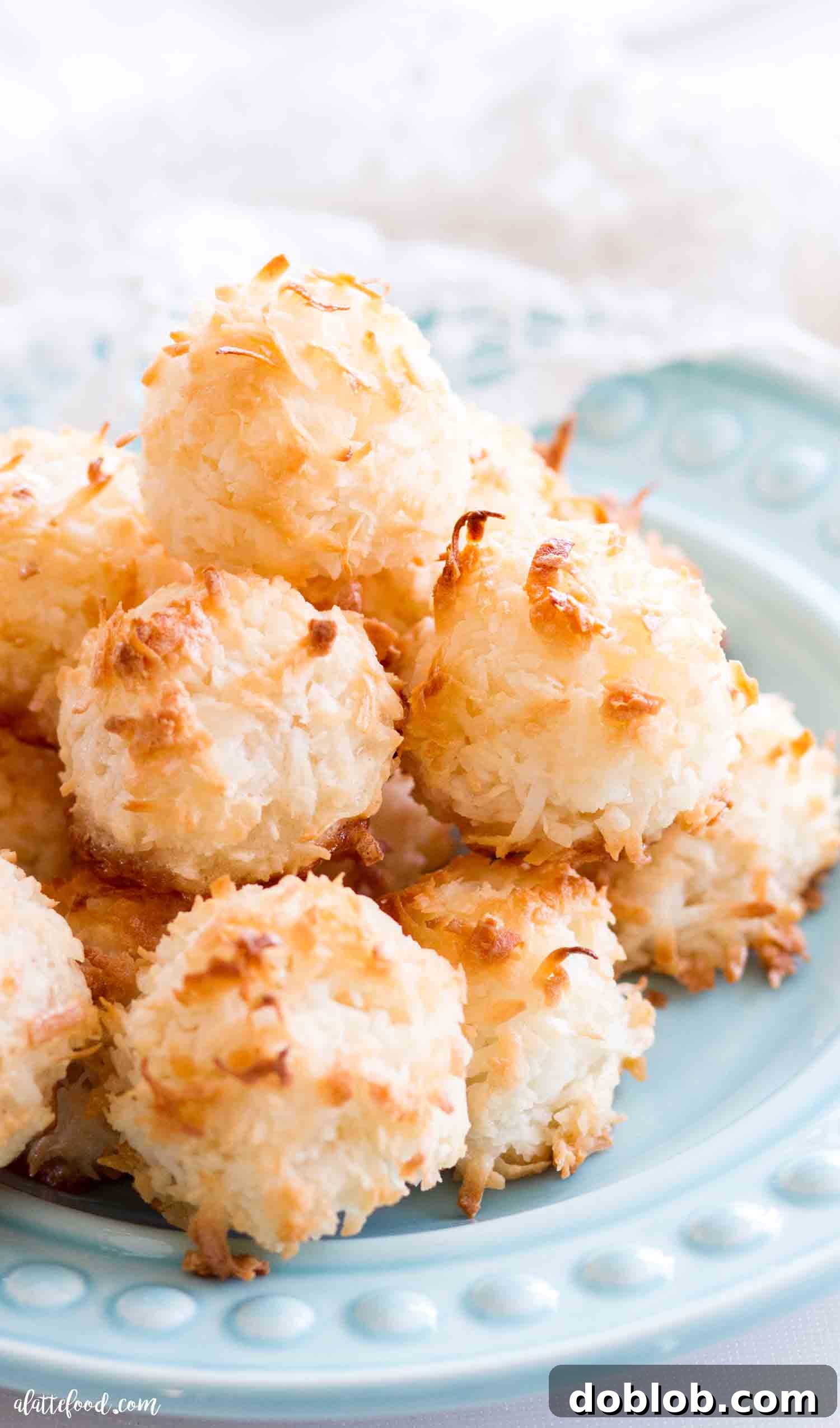 The best homemade macaroons begin with coconut, egg whites and sugar. These are not made with sweetened condensed milk and are made with egg whites instead. A naturally gluten free dessert that's so simple to make! #dessert #coconut #macaroon #recipe Delicious easy homemade coconut macaroons on a blue plate, garnished with chocolate drizzle