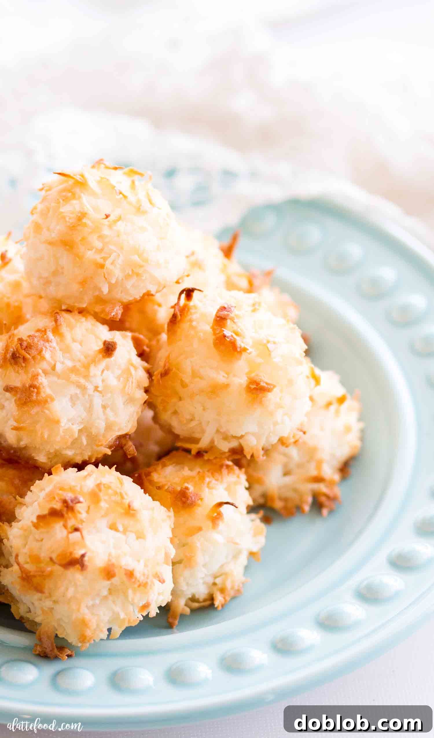 These Easy Coconut Macaroons are made with egg whites (no sweetened condensed milk). These gluten free coconut macaroons are made from scratch and have the best texture. A perfect gluten free dessert! #coconut #macaroon #cookie #dessert Easy coconut macaroons stacked artfully on a teal plate, highlighting their appealing golden color