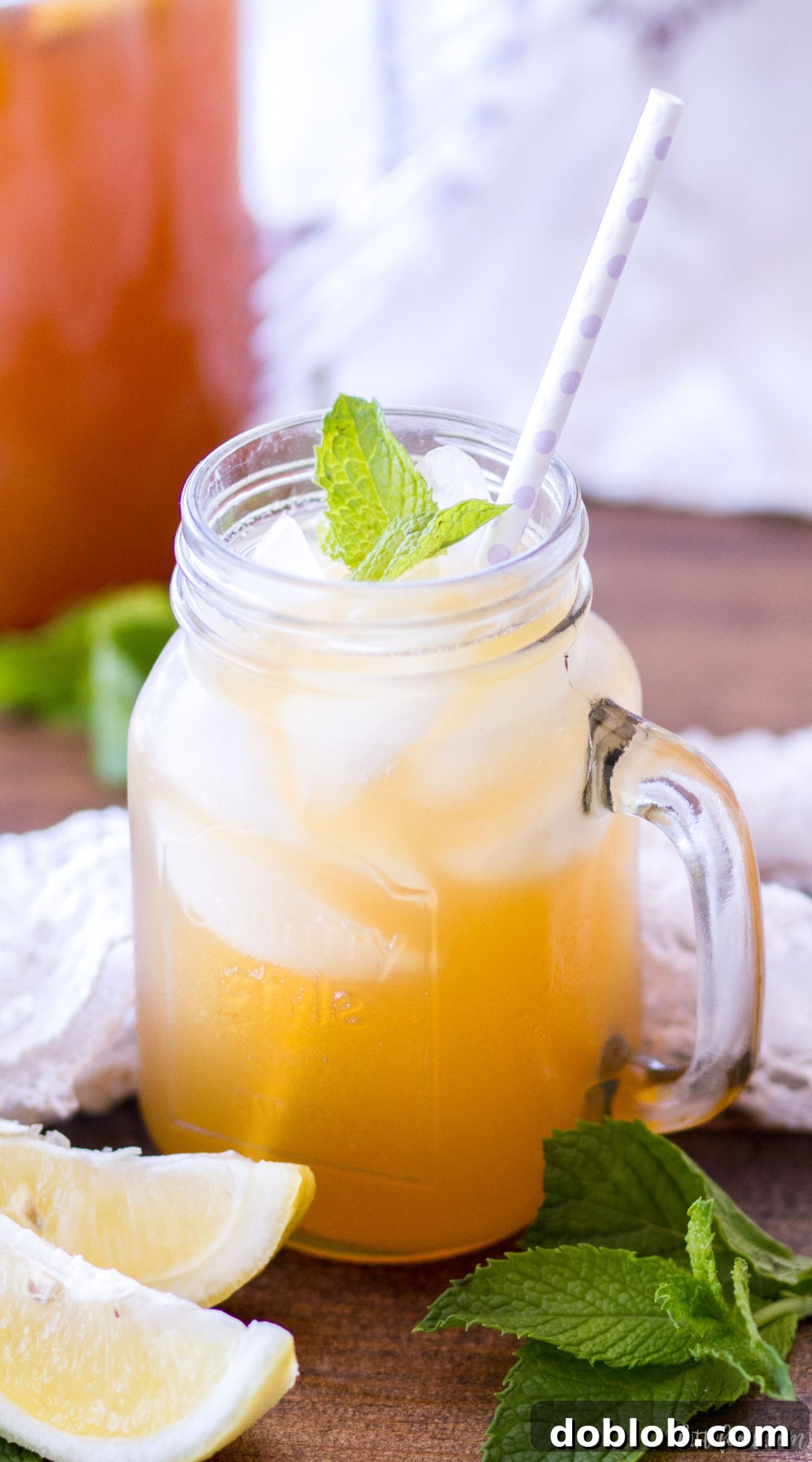 Homemade Iced Peach Green Tea, naturally sweetened for summer. Close-up of a glass with ice, peach slices, mint, and green tea.